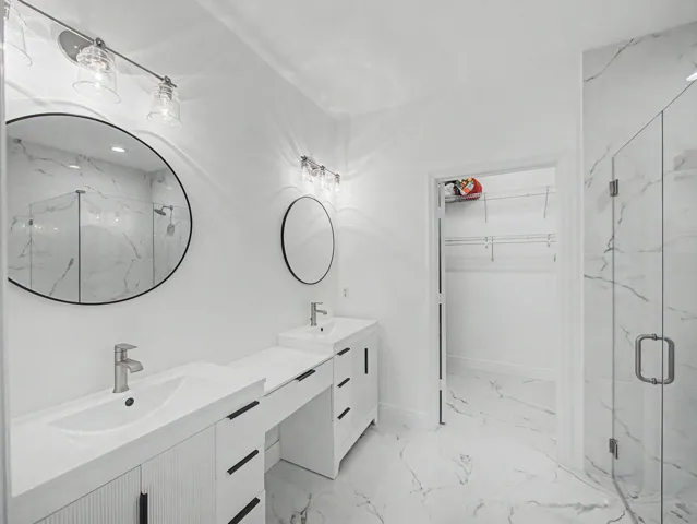 Spa-inspired primary bathroom featuring a dual-sink vanity with integrated storage, polished quartz countertop, and matte black fixtures