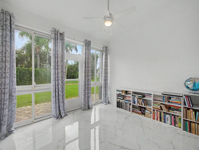 Bright, light-filled room showcasing expansive glass doors framing manicured lawn and mature landscaping
