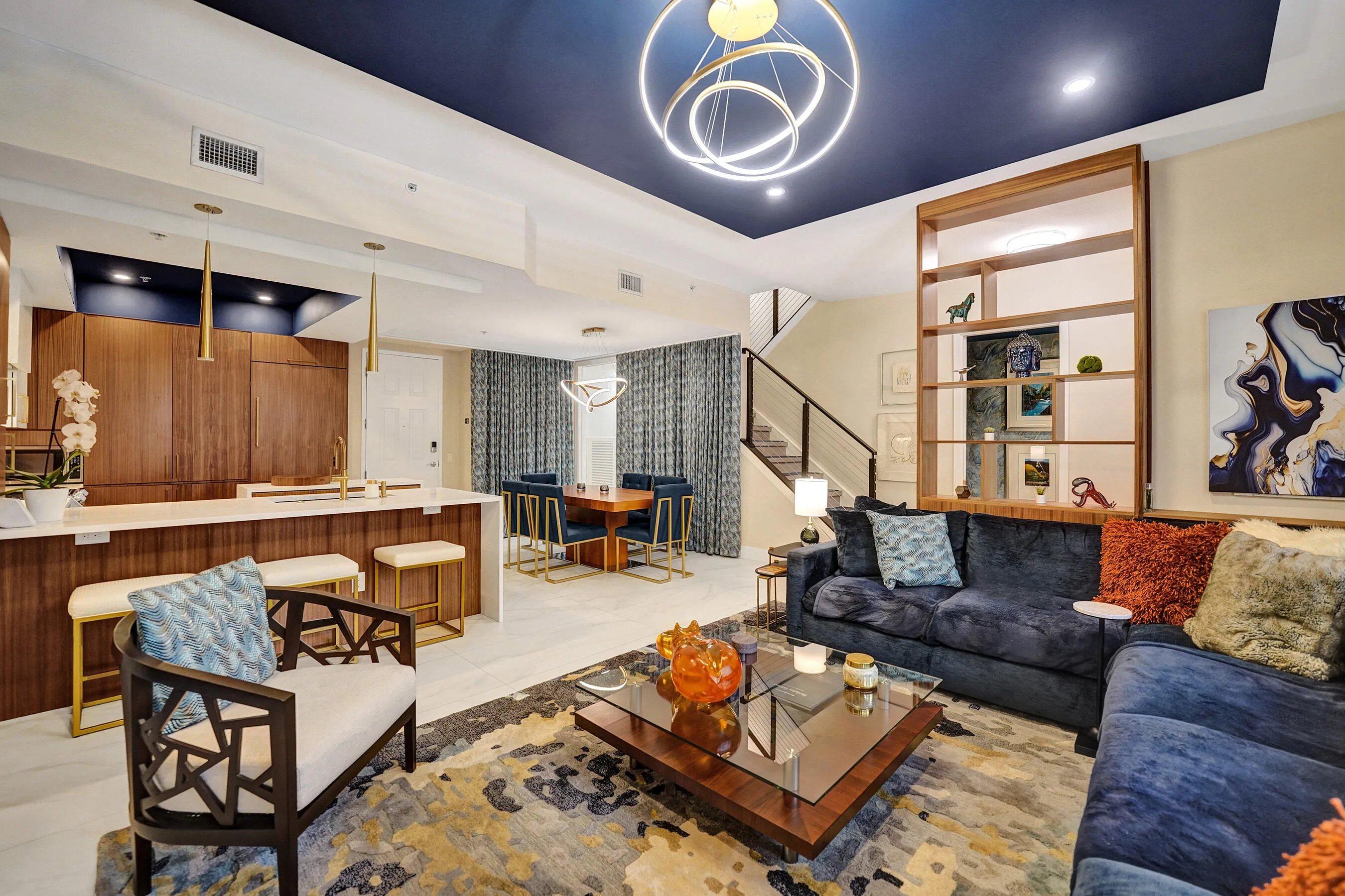 Open-concept living area with a dark blue accent ceiling, wood-finish cabinetry, and a kitchen island with seating