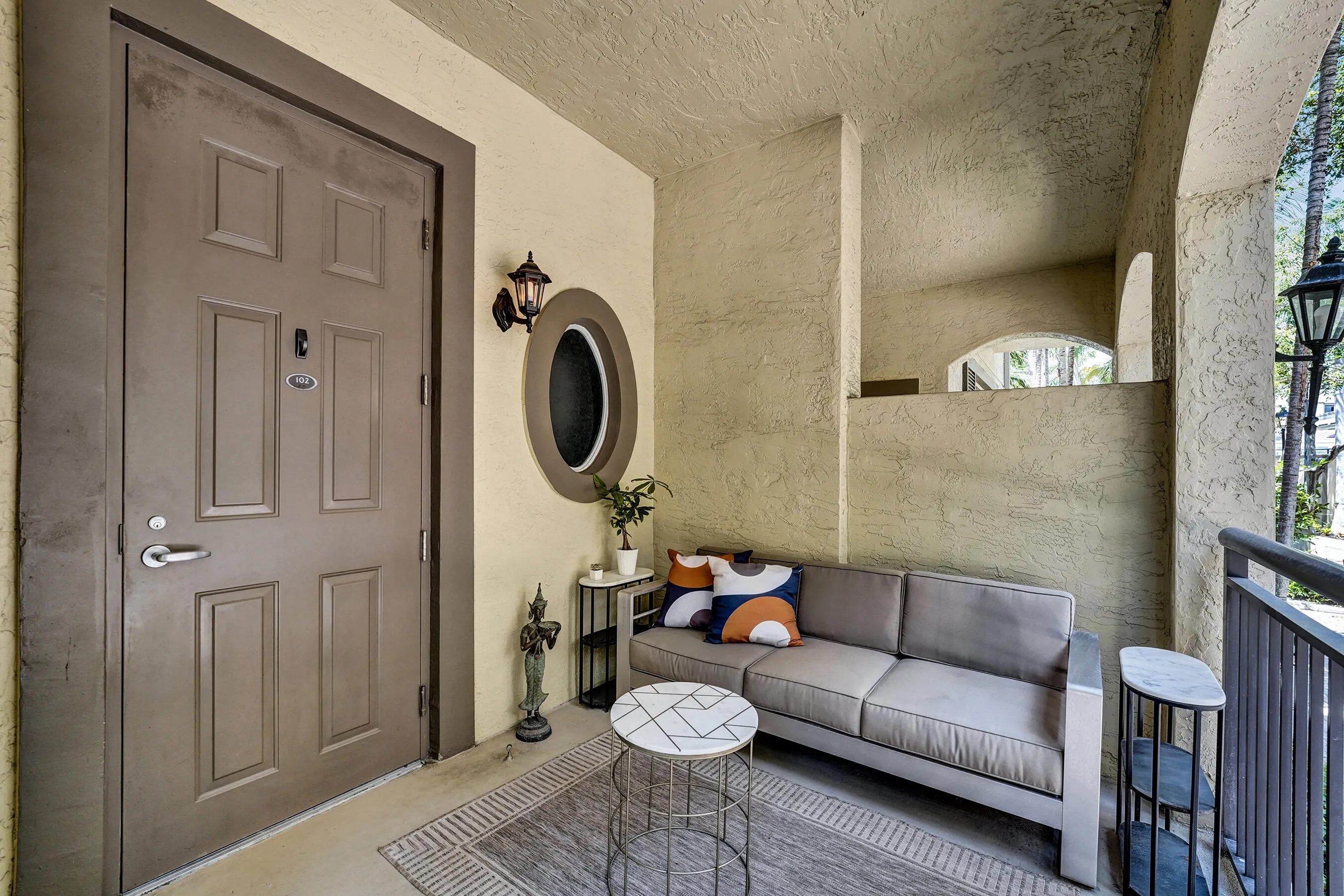 Covered patio with textured walls, an arched architectural element, and outdoor lighting