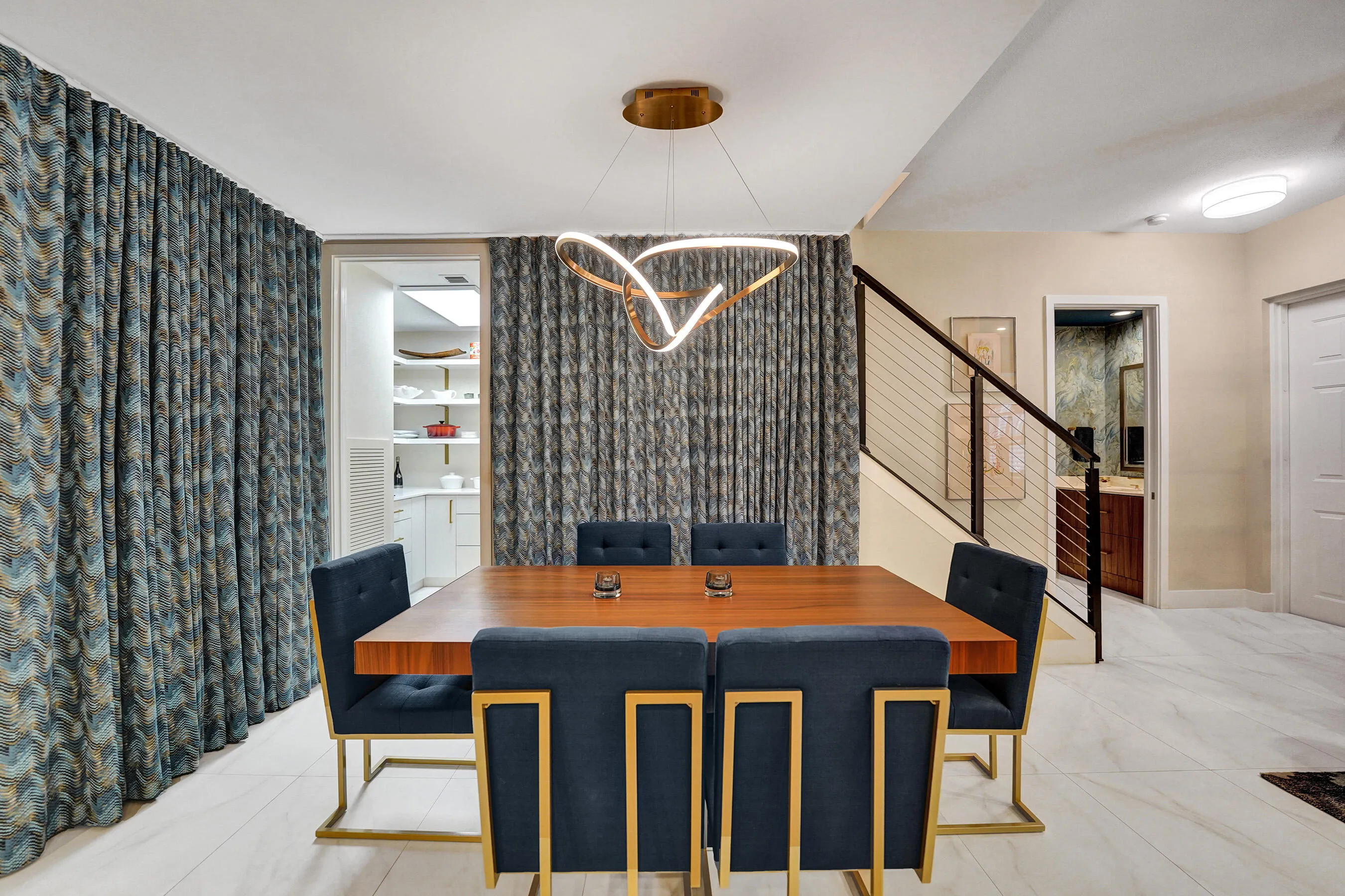 Dining area with a modern chandelier, staircase with cable railing, and light-toned flooring
