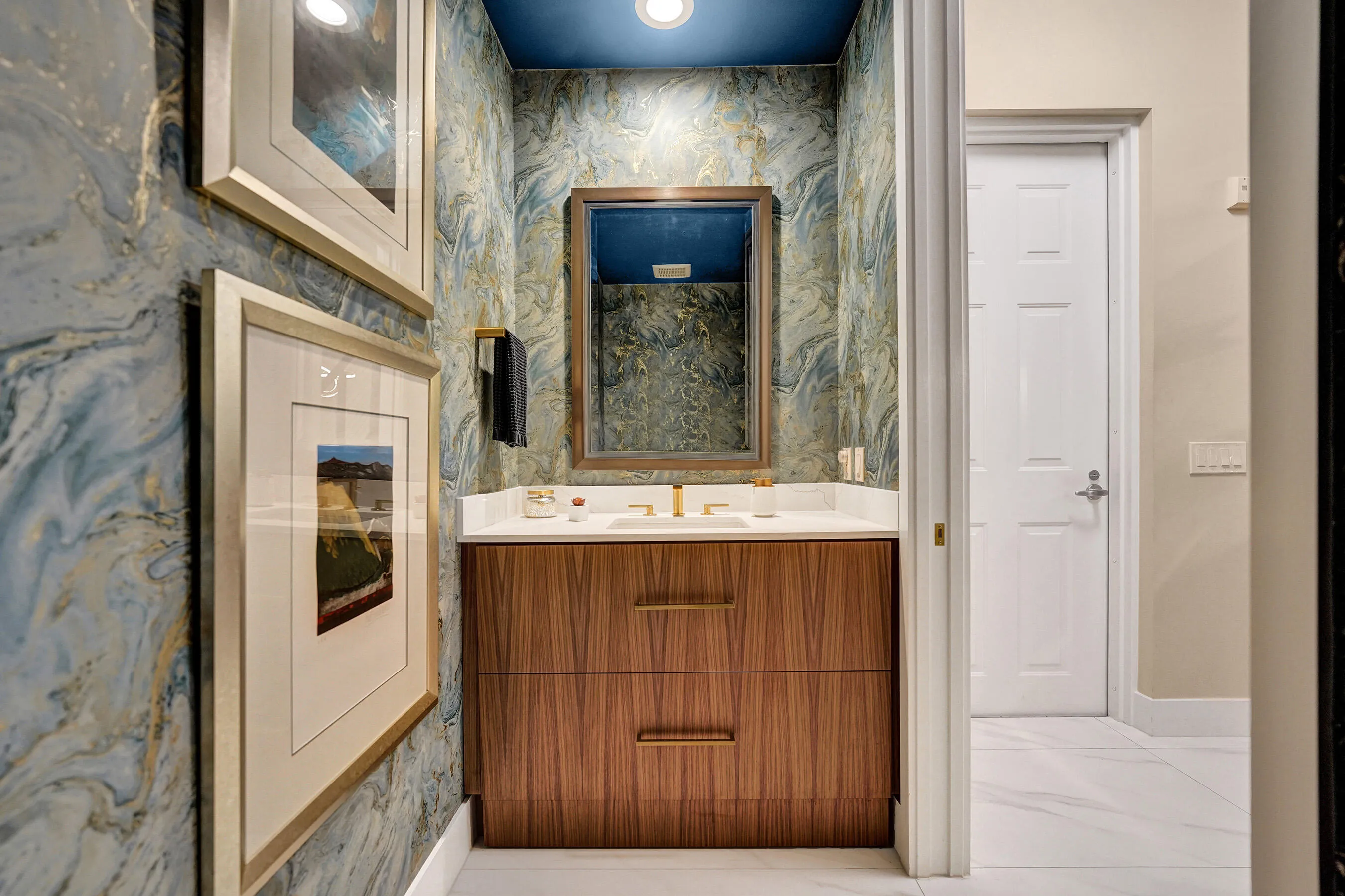 Built-in vanity with wood-finish cabinetry, a white countertop, and a recessed sink with gold-finish faucet