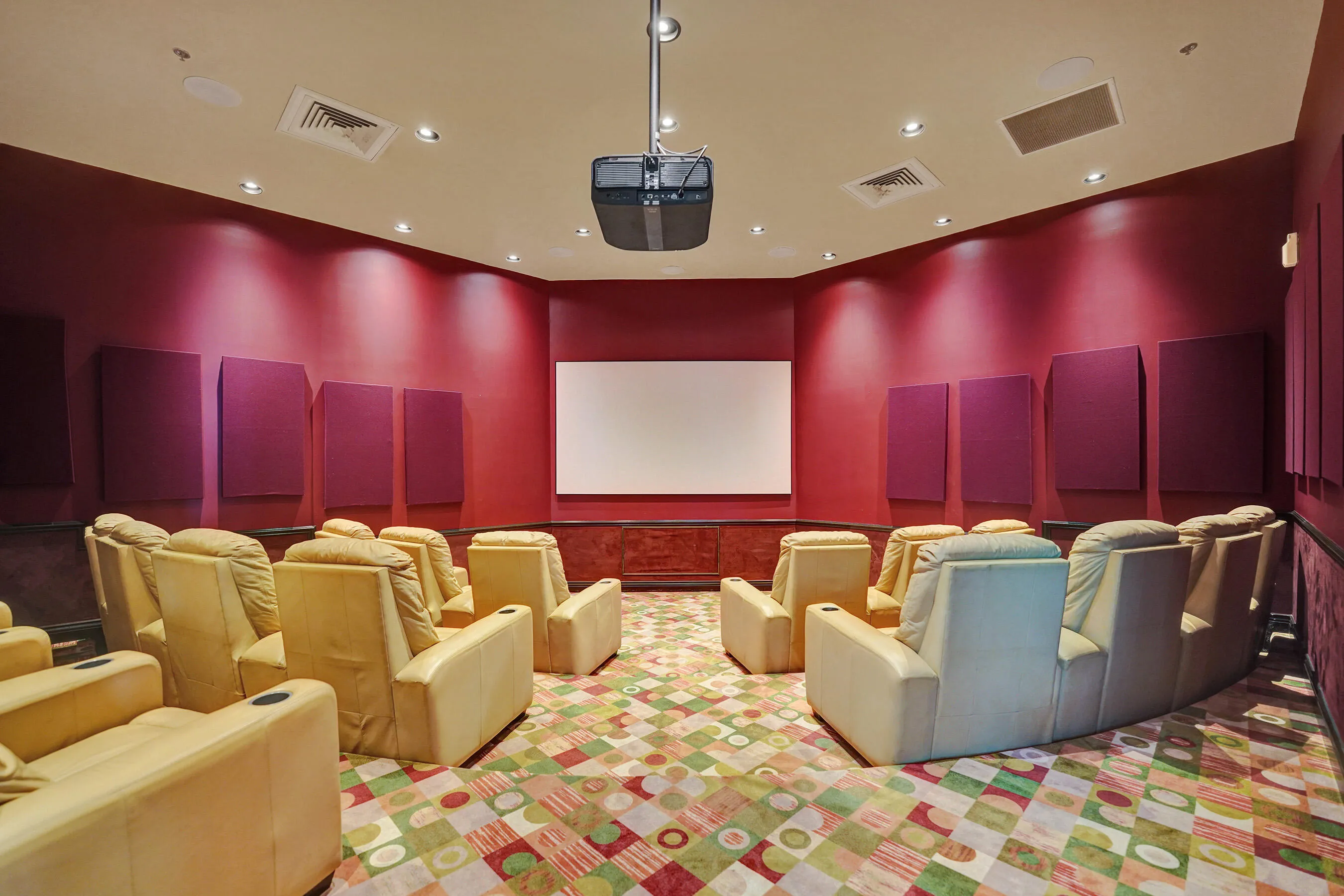 Dedicated media room with wall-mounted acoustic panels, recessed lighting, and a ceiling-mounted projector