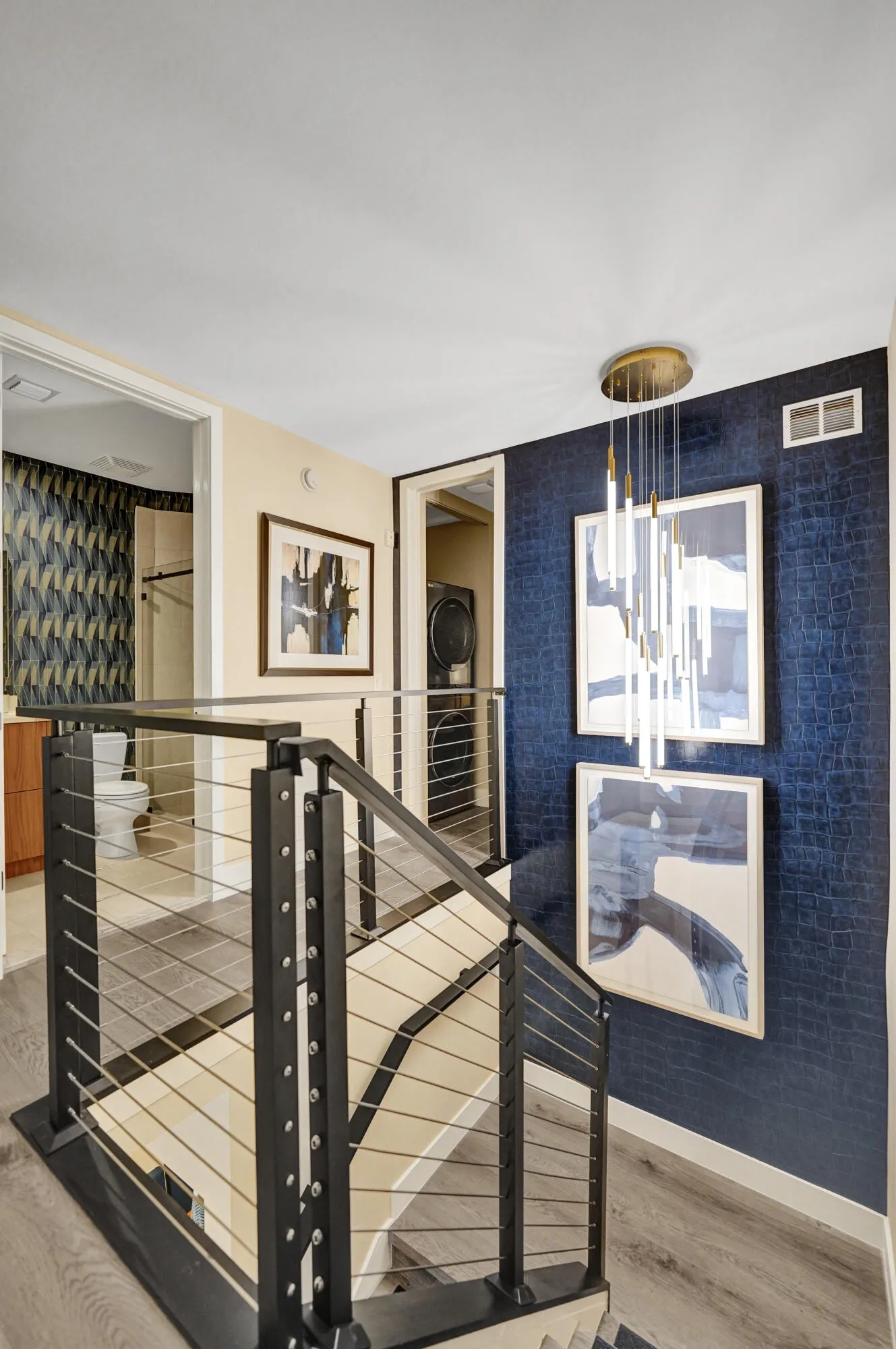 Modern cable railing system, wood-finish flooring, deep blue accent wall, and contemporary ceiling light fixture
