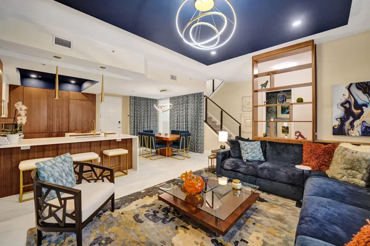 Open-concept living area with a dark blue accent ceiling, wood-finish cabinetry, and a kitchen island with seating