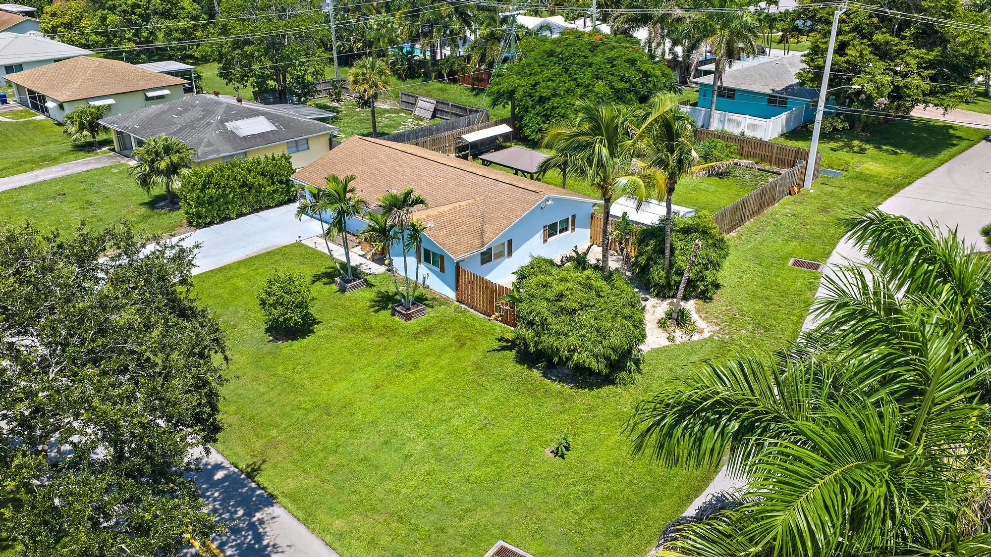 Single-story residence with a brown shingle roof, light blue exterior siding, and a paved driveway