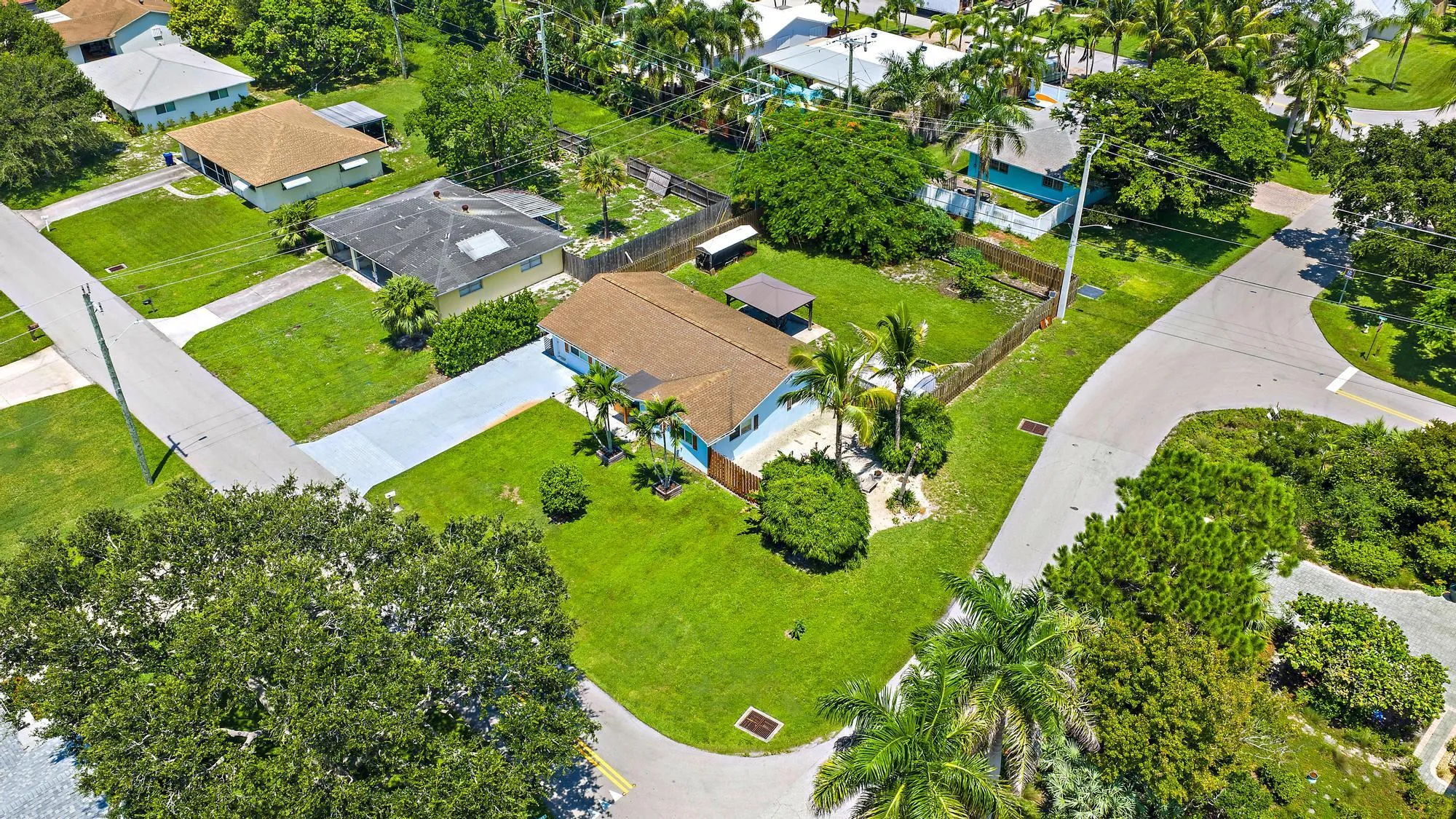 Expansive corner lot with a manicured lawn, established landscaping, and a fenced perimeter