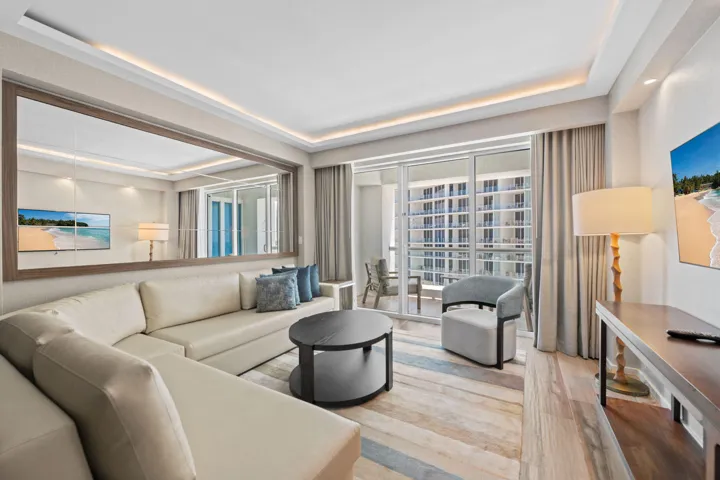 Expansive living space featuring a full-wall mirror, wood-finish flooring, and recessed ceiling lighting