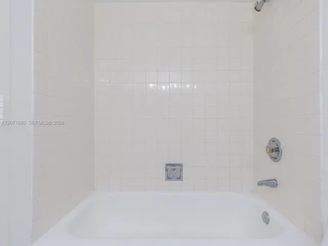 Clean and bright full bath featuring a traditional tub and shower combination with classic tilework.