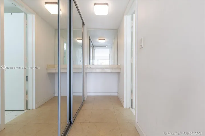 Primary suite hallway offering wall-to-wall mirrored closets and seamless flow into the private bath.