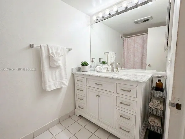 Primary en-suite bathroom featuring an expansive vanity with marble-look counter and ample storage.