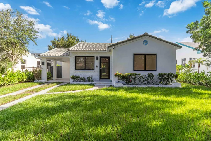 White stucco exterior with black-framed windows, a covered carport, and a tile roof
