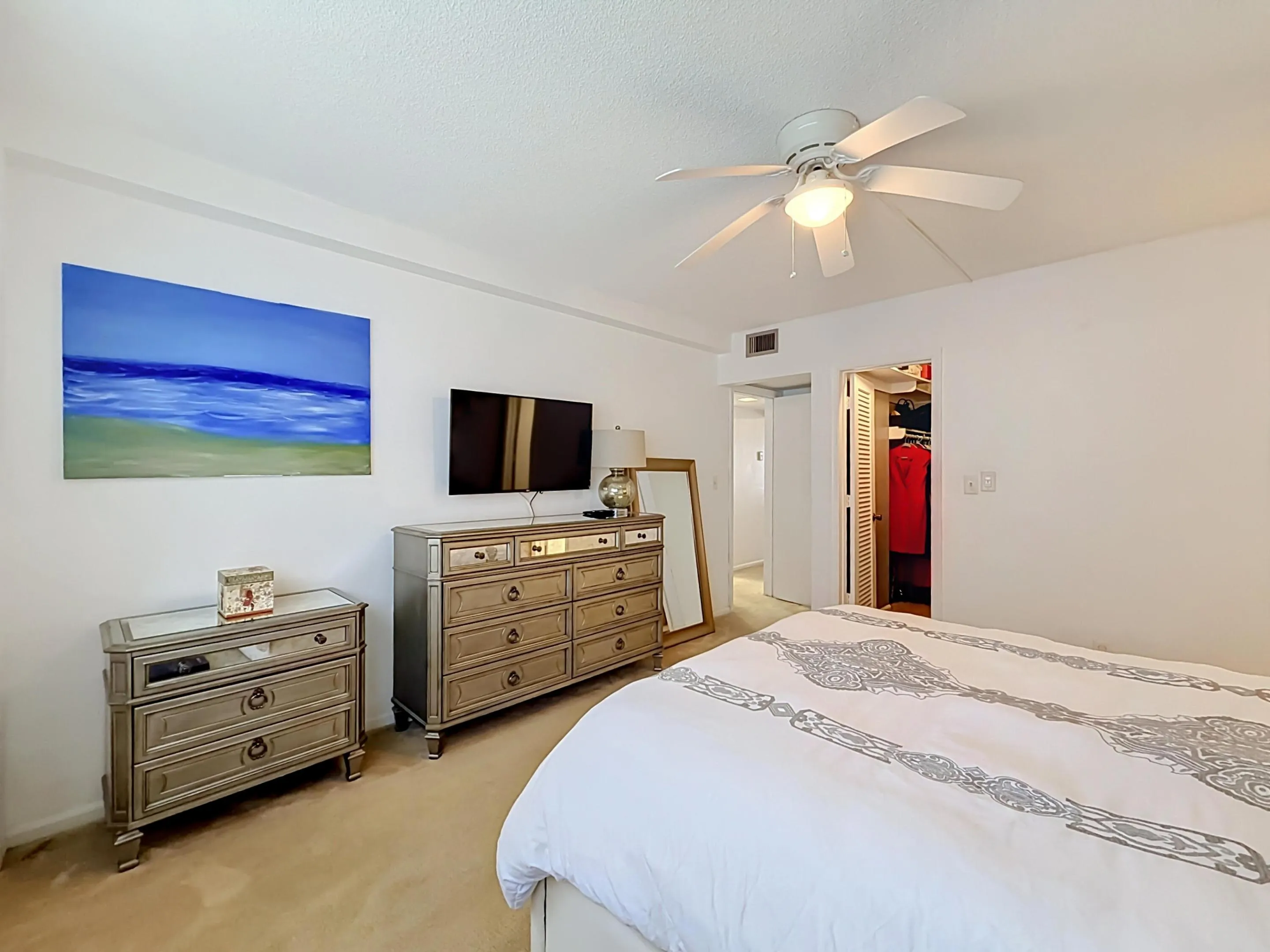 Ceiling fan with integrated lighting, wall-to-wall carpeting, and a bi-fold closet door