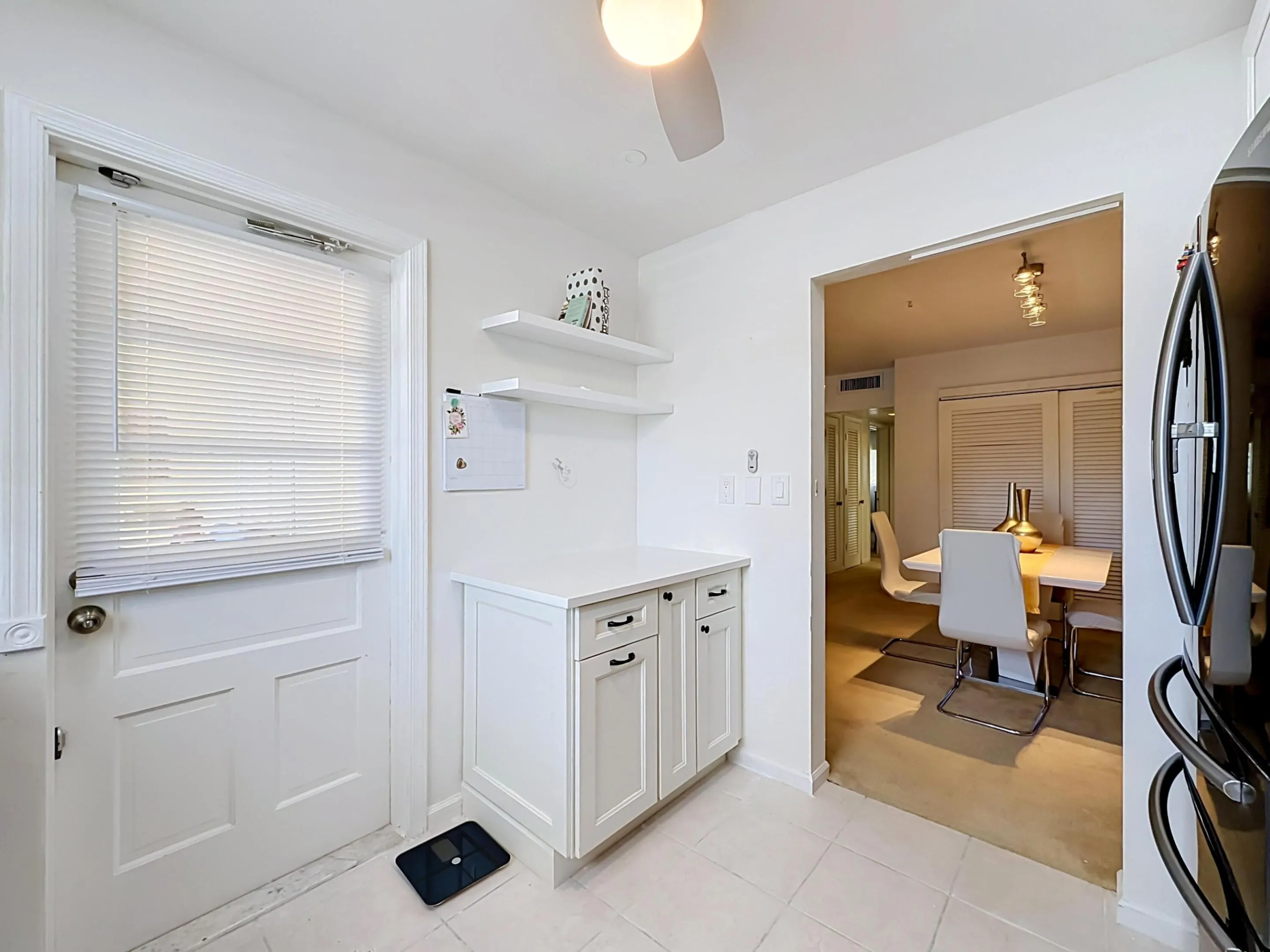 White shaker-style cabinetry with dark hardware, solid surface countertop, and open shelving