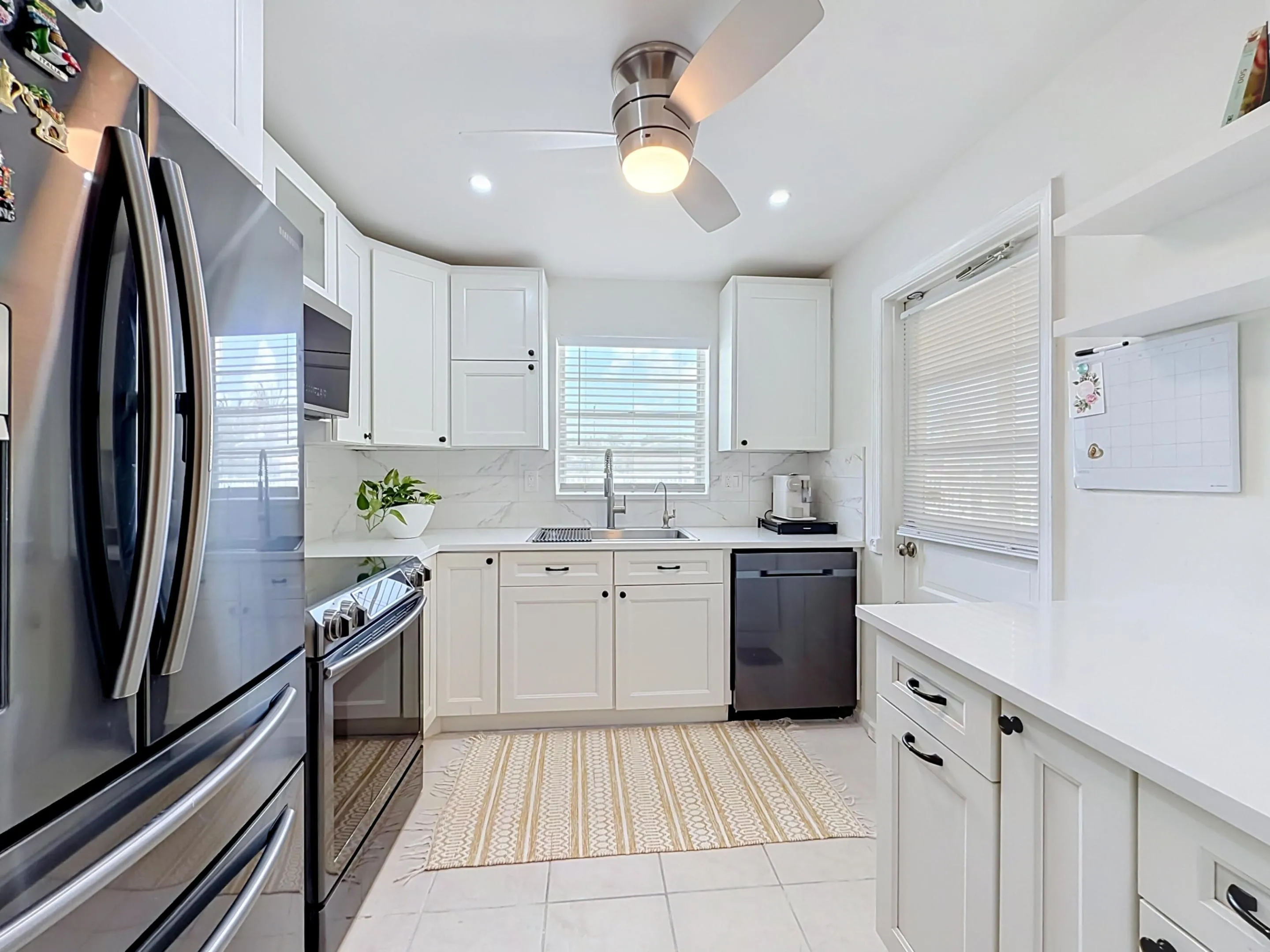 White shaker cabinetry, recessed lighting, ceiling fan with illumination, stainless steel appliances, and a solid surface countertop