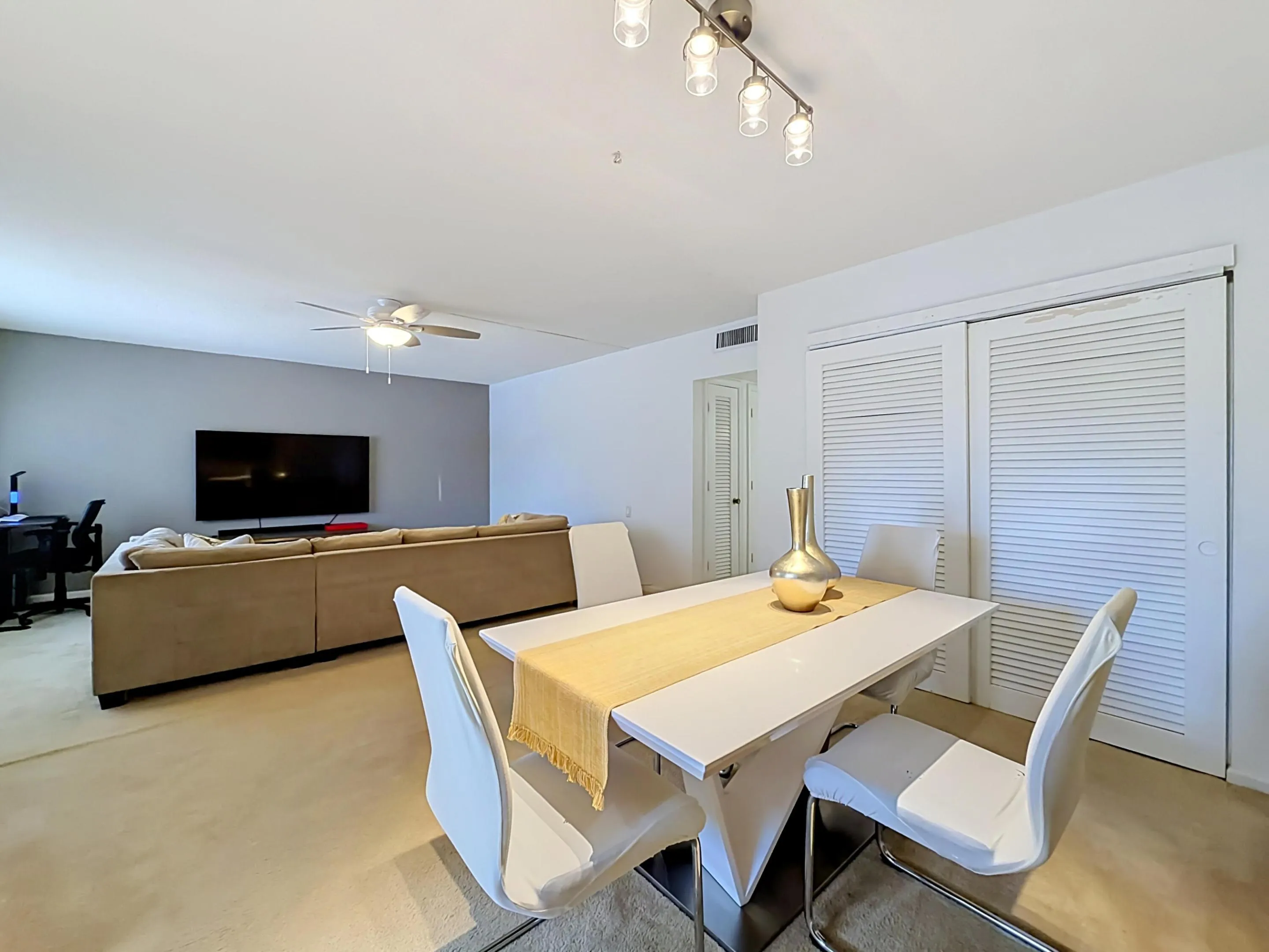 Open-concept living space with a dining area, ceiling fan, and louvered bifold doors
