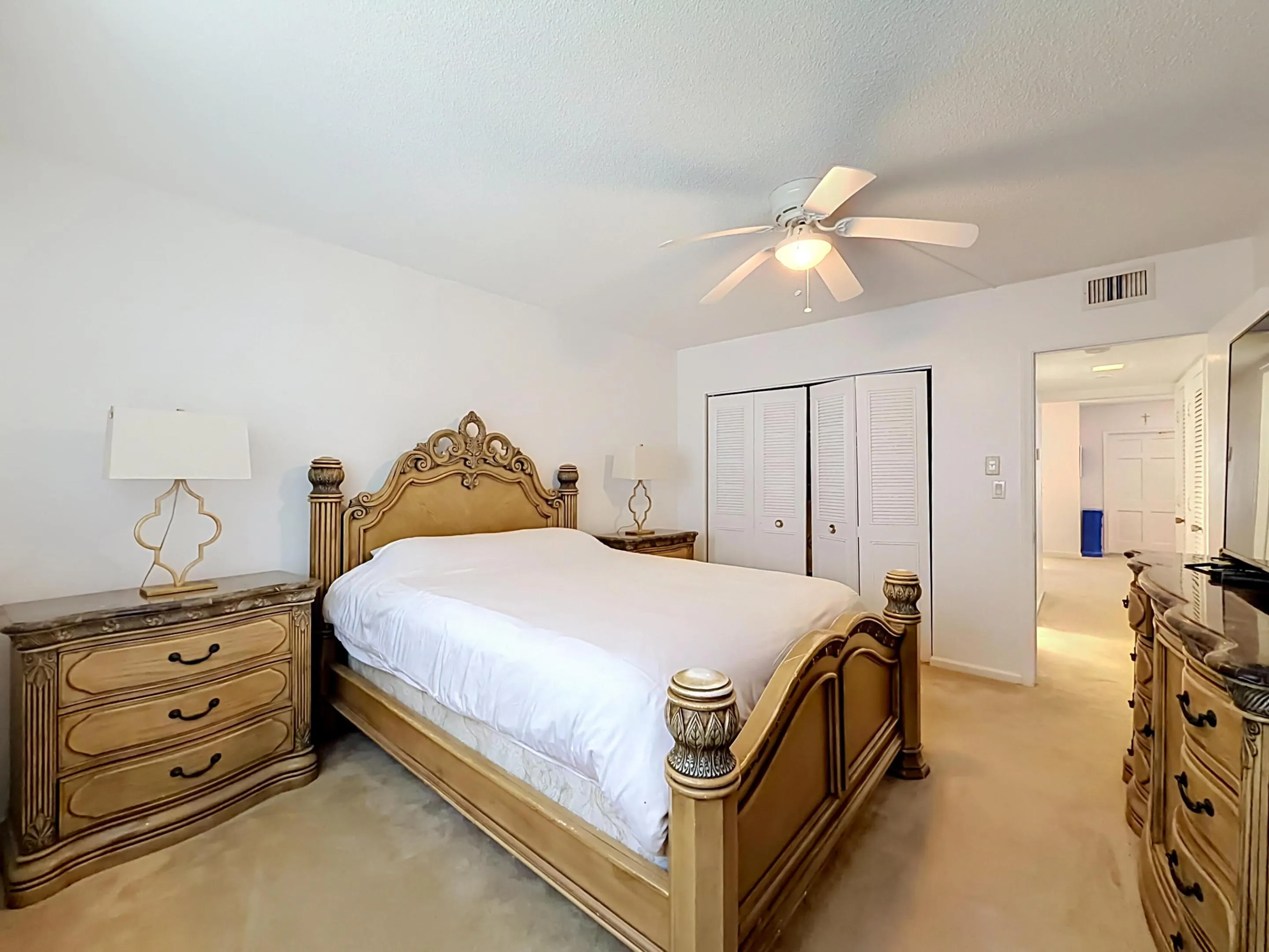 White walls throughout, ceiling fan with integrated lighting, and carpeted flooring