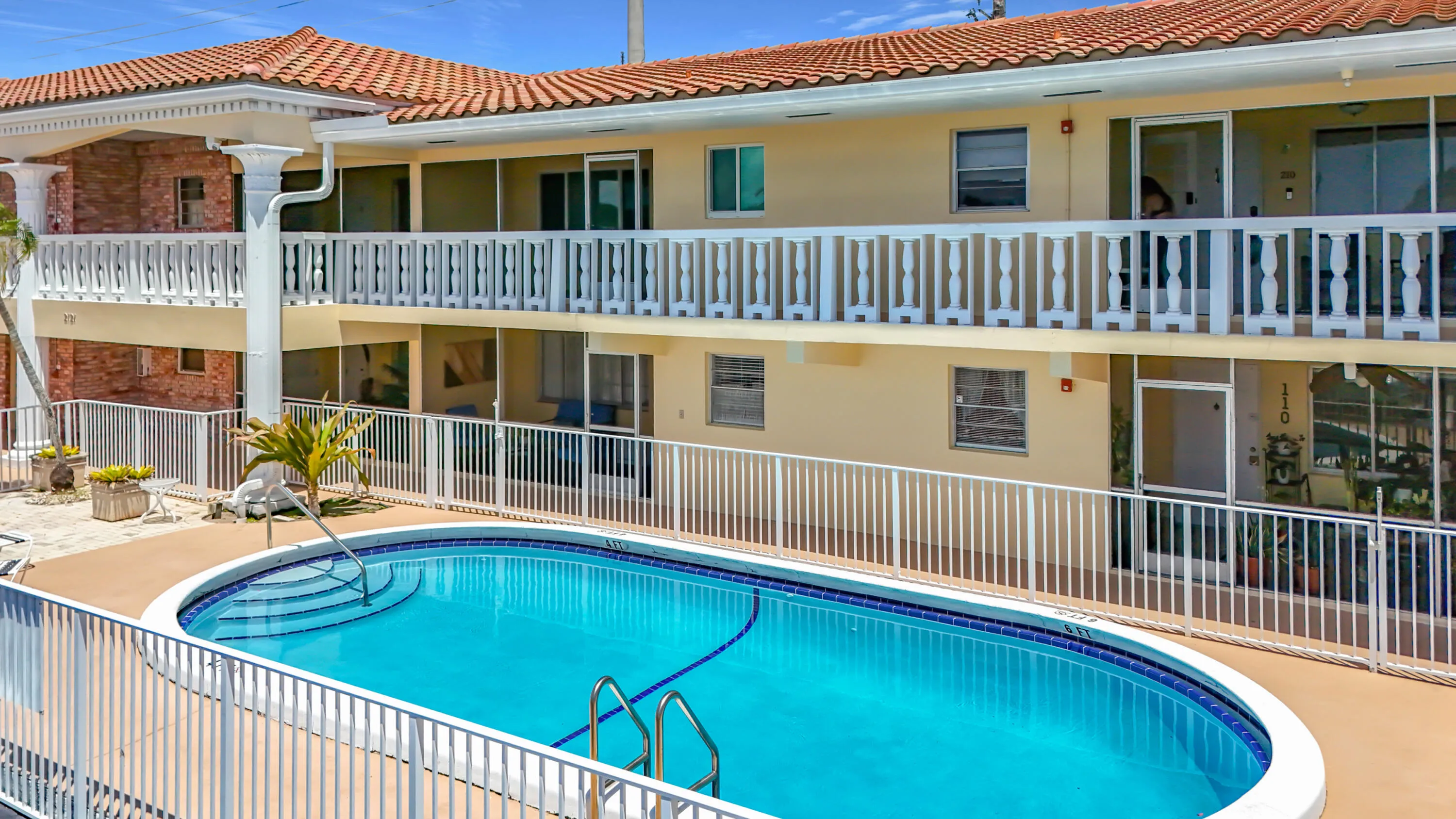 Multi-story building featuring a red tile roof and multiple balconies with white balustrades