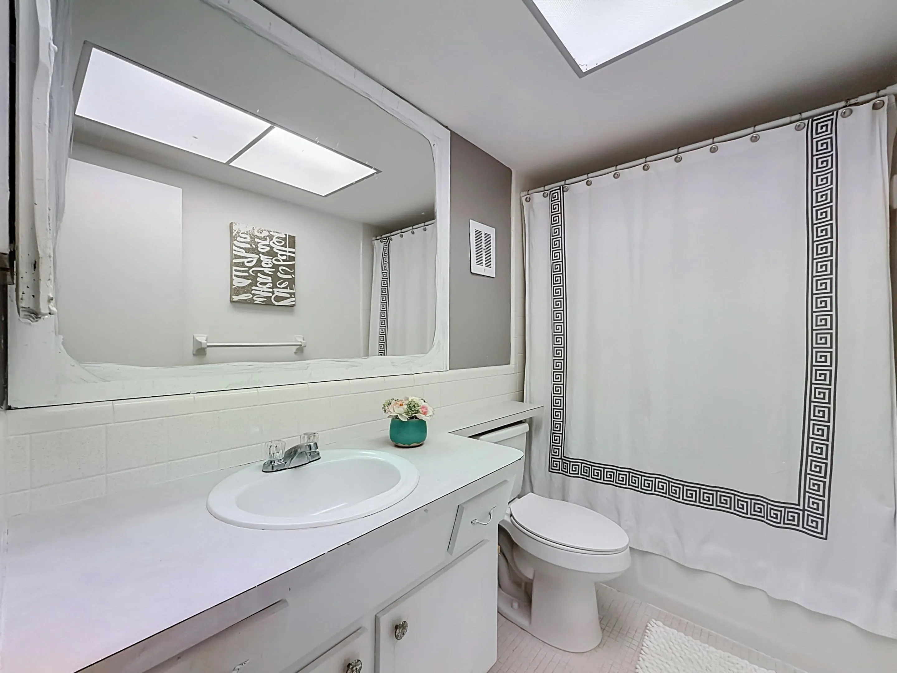 Integrated vanity with basin sink, mirrored wall, and overhead lighting