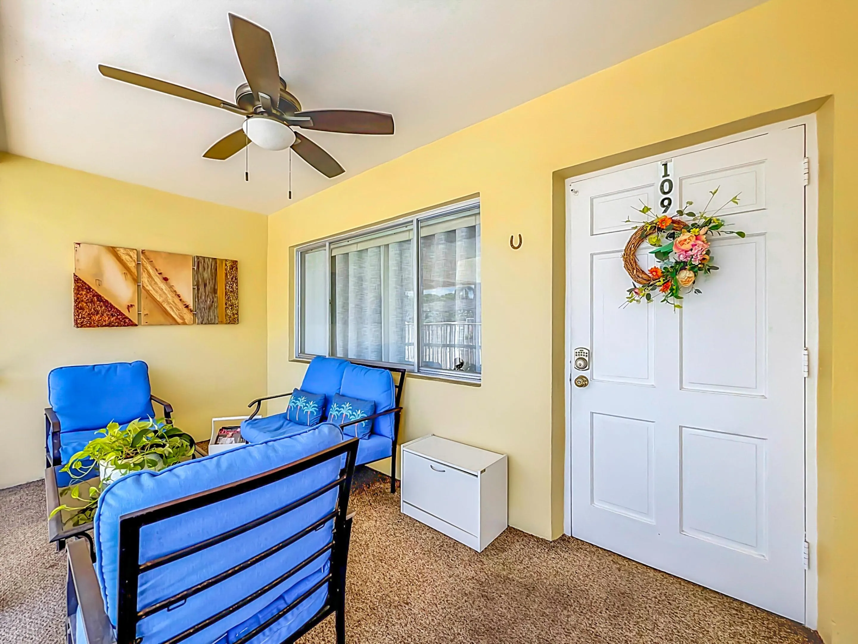 Covered porch with a ceiling fan, a white paneled entry door, and a horizontal window