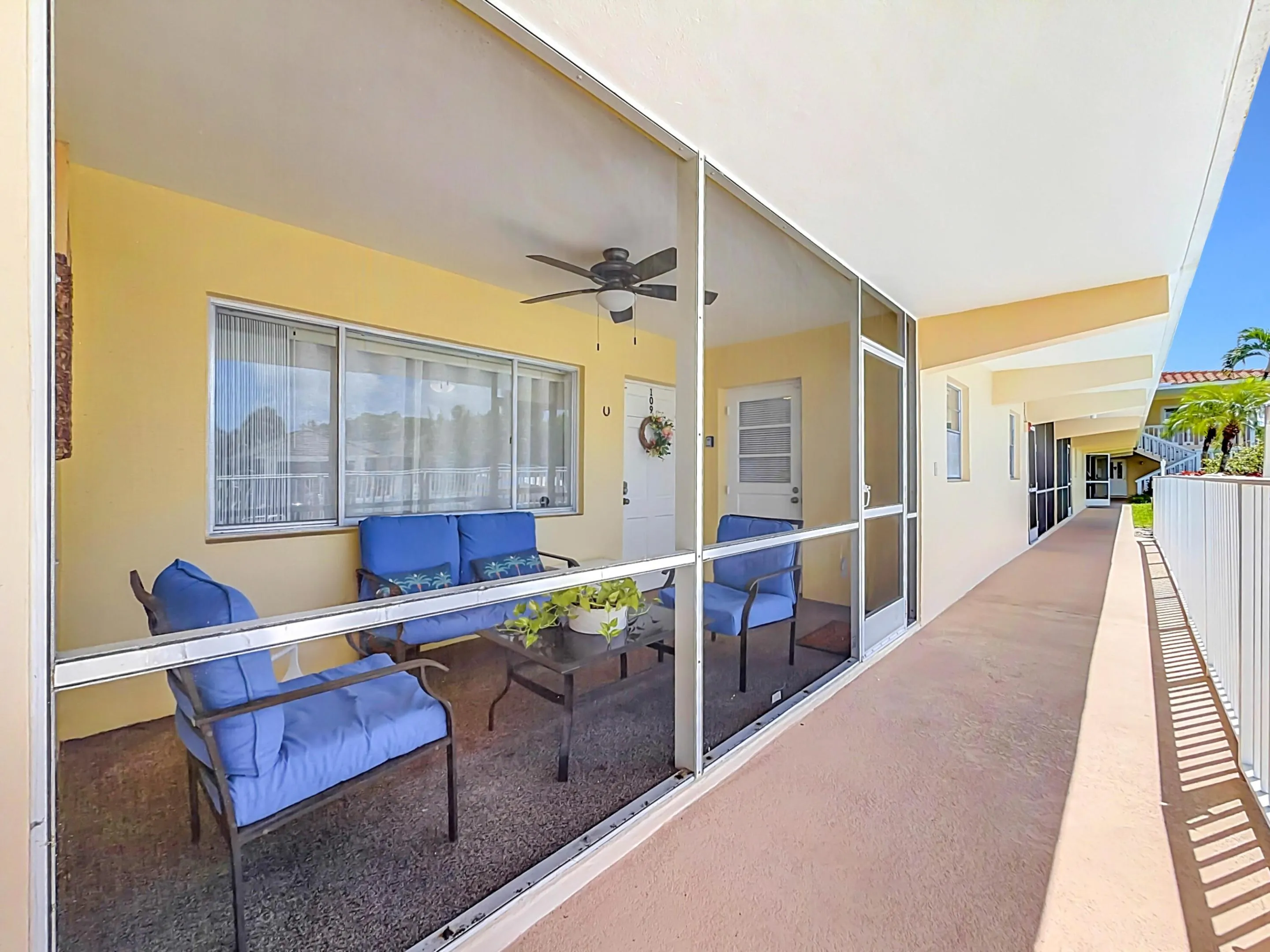 Screened outdoor living area with a ceiling fan, sliding windows, and a private entrance