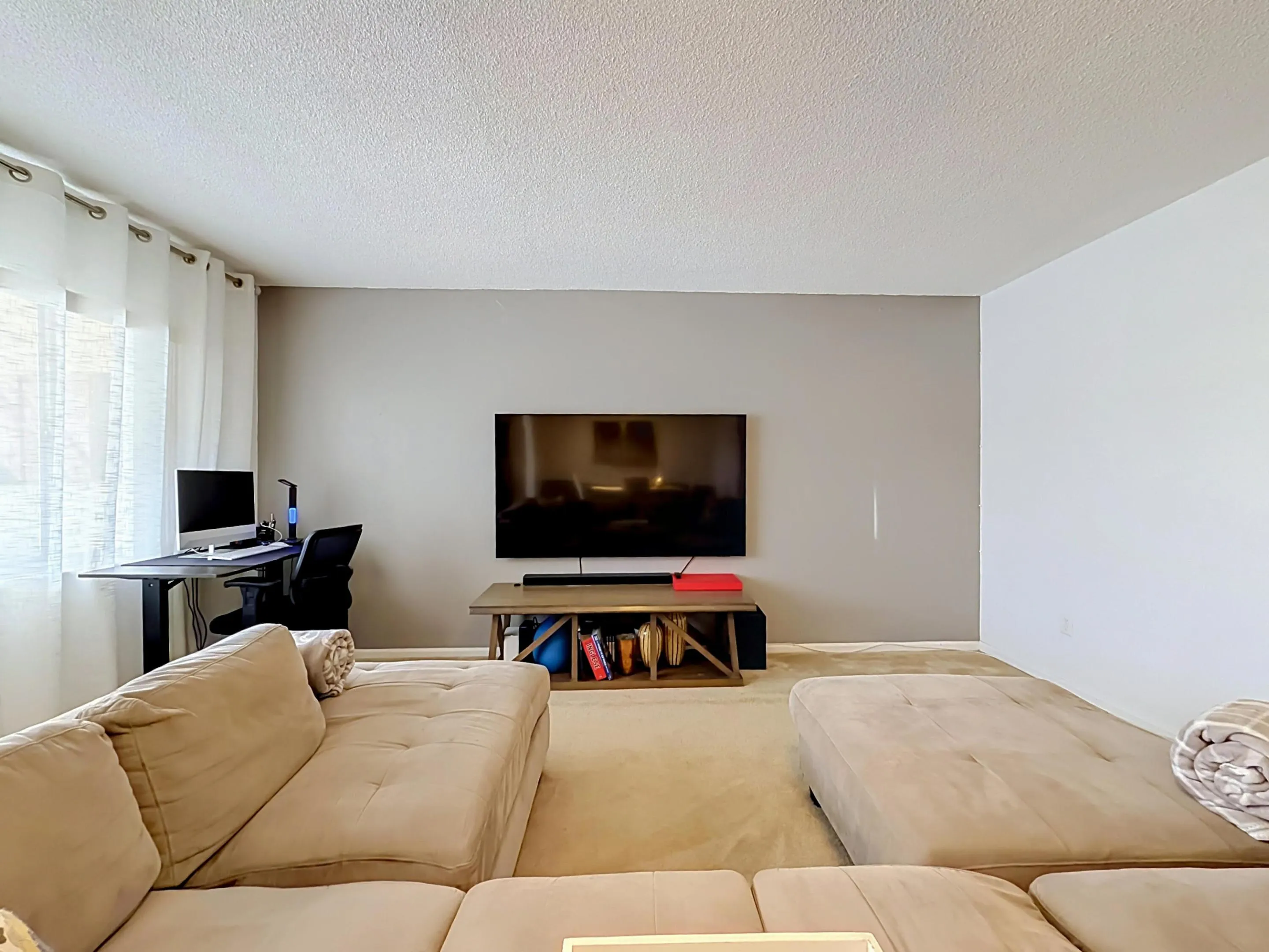 Recessed lighting, textured ceiling, light-toned carpeting, ample wall space, and a window with sheer drapes