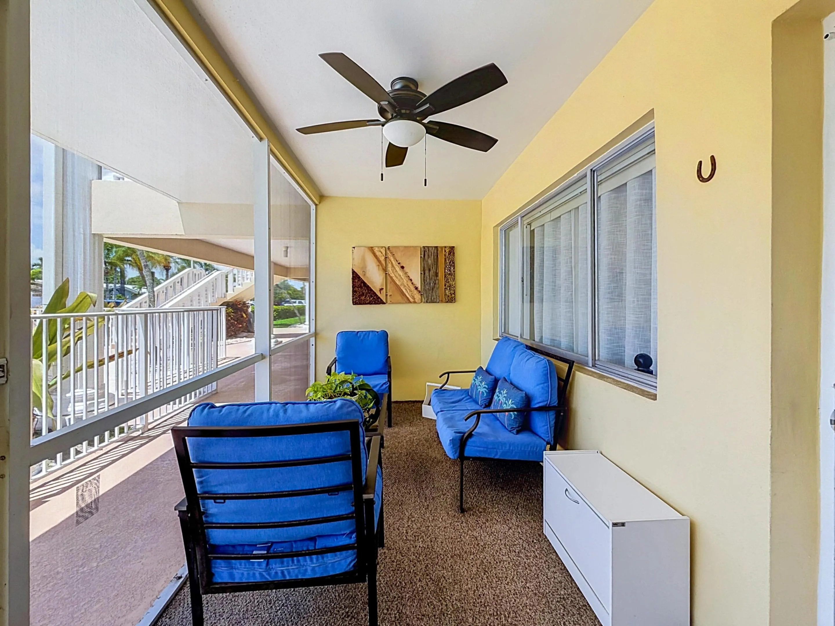 Screened outdoor living space featuring a ceiling fan, textured flooring, and a large window