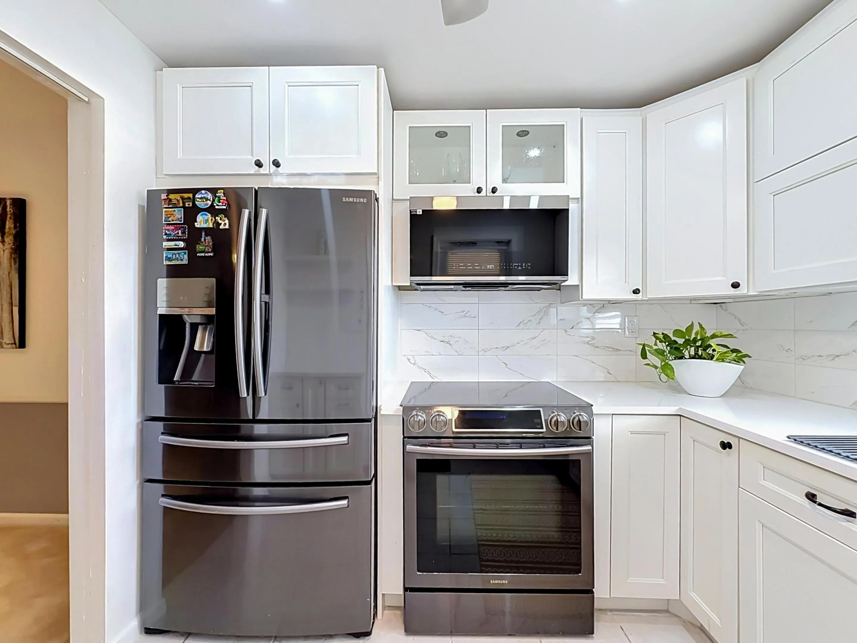 White shaker-style cabinetry with black hardware, white countertops, and a white tile backsplash