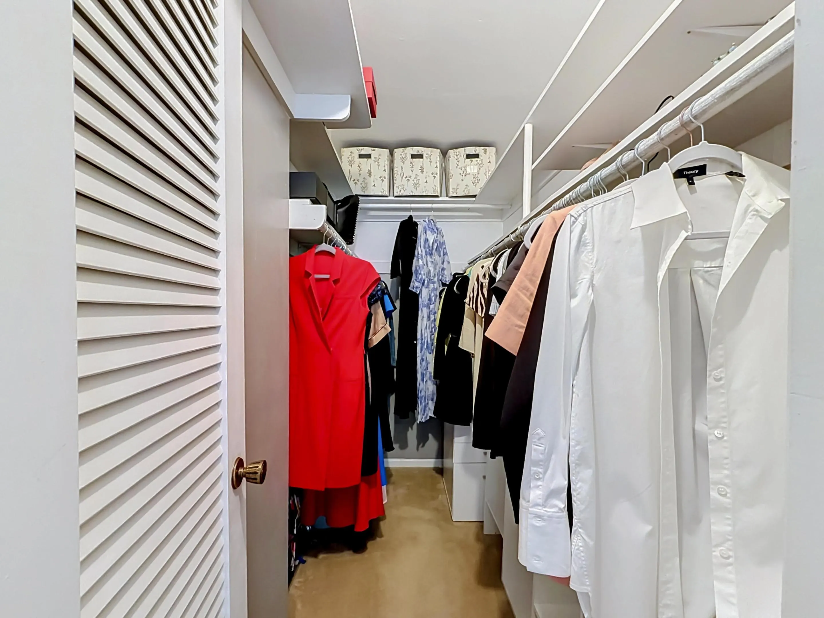 Walk-in closet with built-in shelving, integrated hanging rods, and louvered bifold door