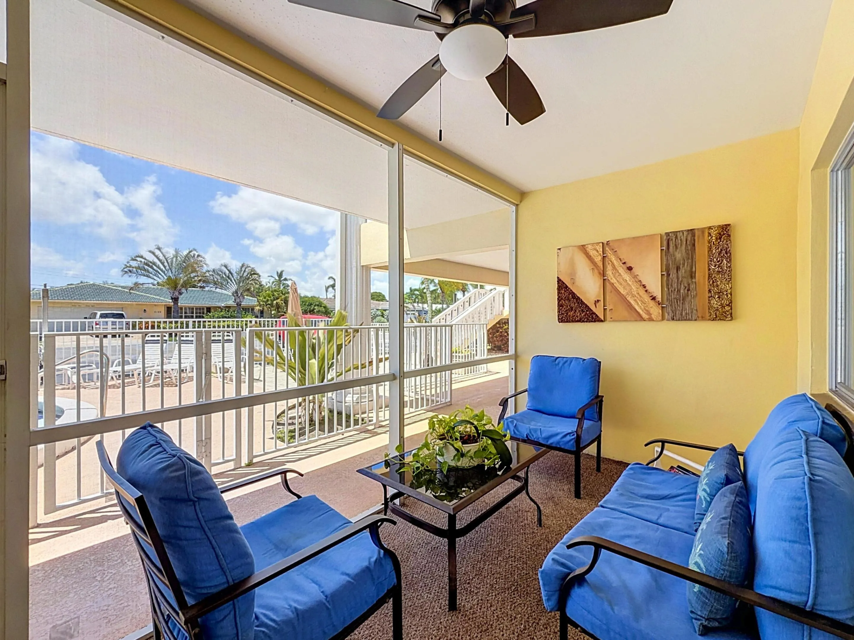 Screened outdoor living area featuring a ceiling fan, textured flooring, and a railing enclosure