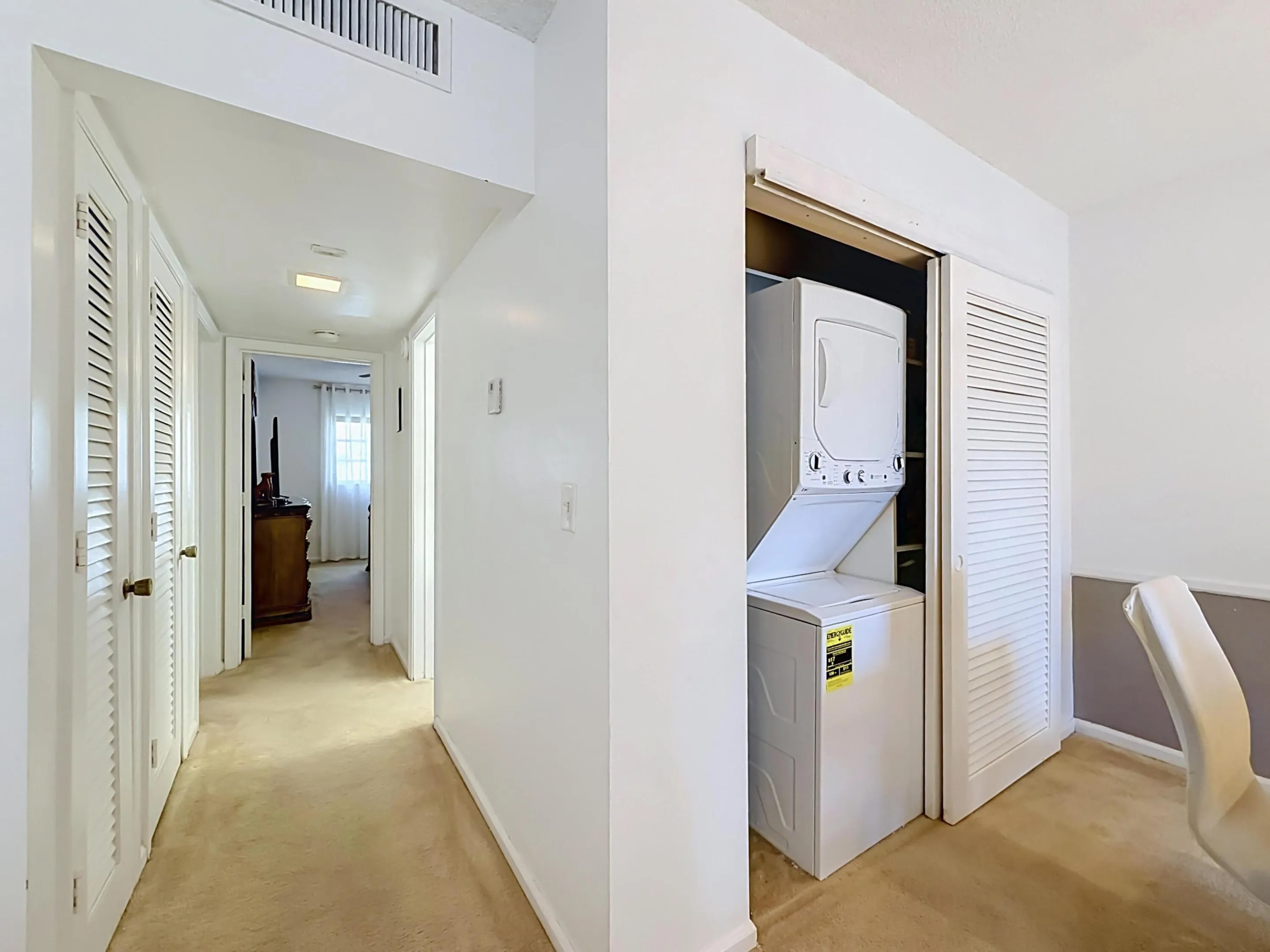 Hallway featuring neutral-toned carpeting, white louvered closet doors, and recessed lighting