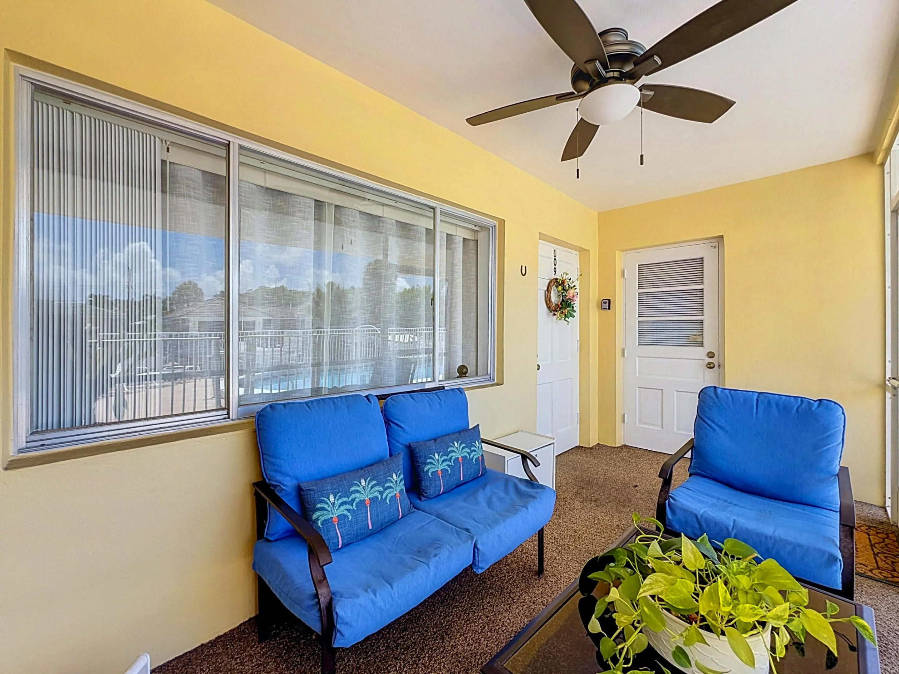 Screened patio with a ceiling fan, dual entry doors, and views of the outdoor pool area