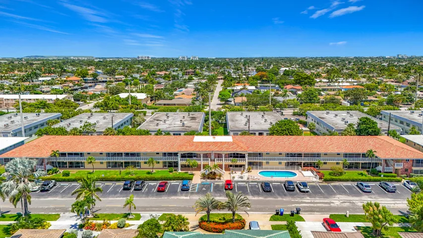 Multi-unit building featuring a terracotta tile roof, private balconies, and an outdoor swimming pool
