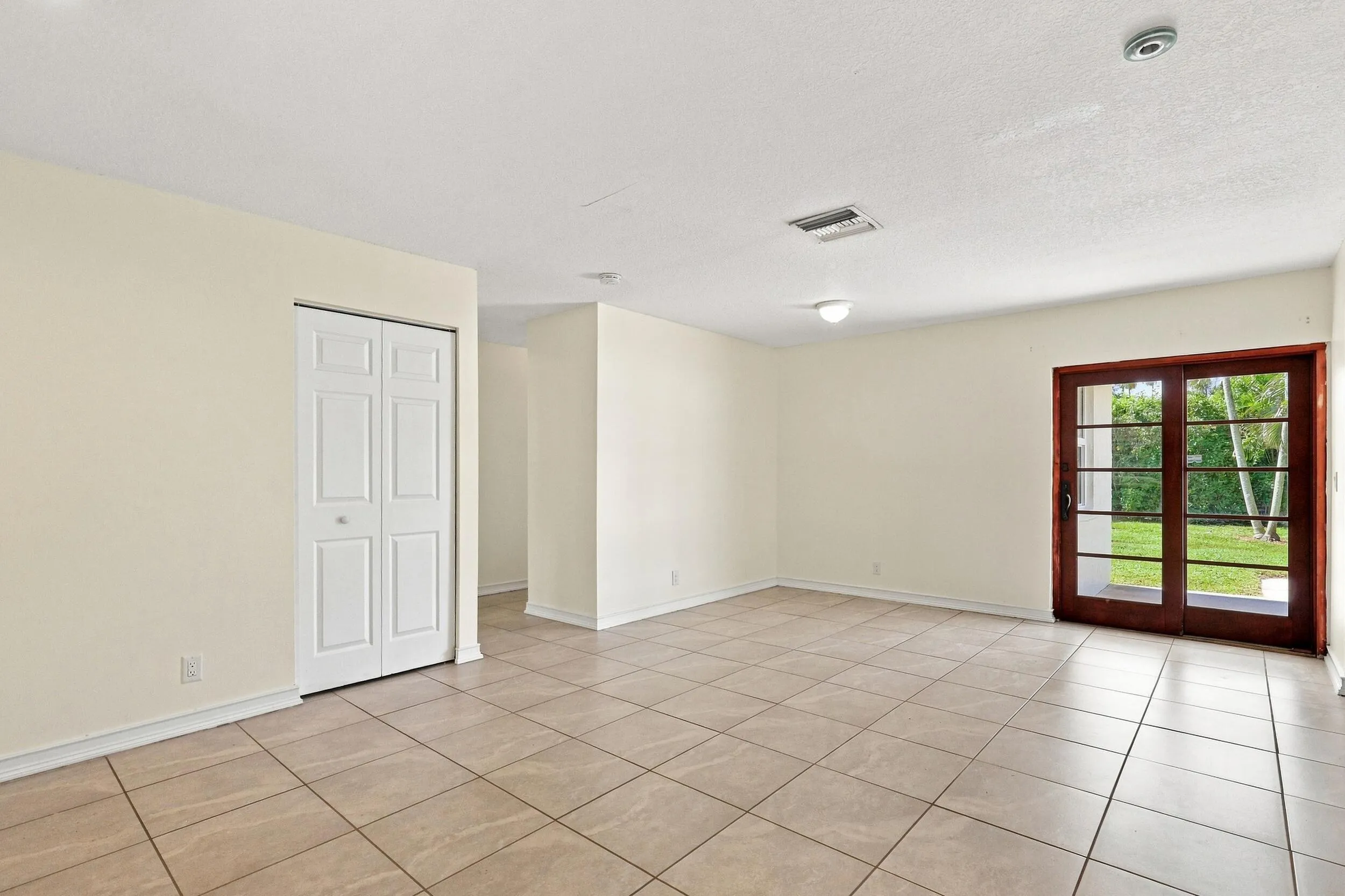 Bright, open living space with tile flooring and French doors providing natural light.