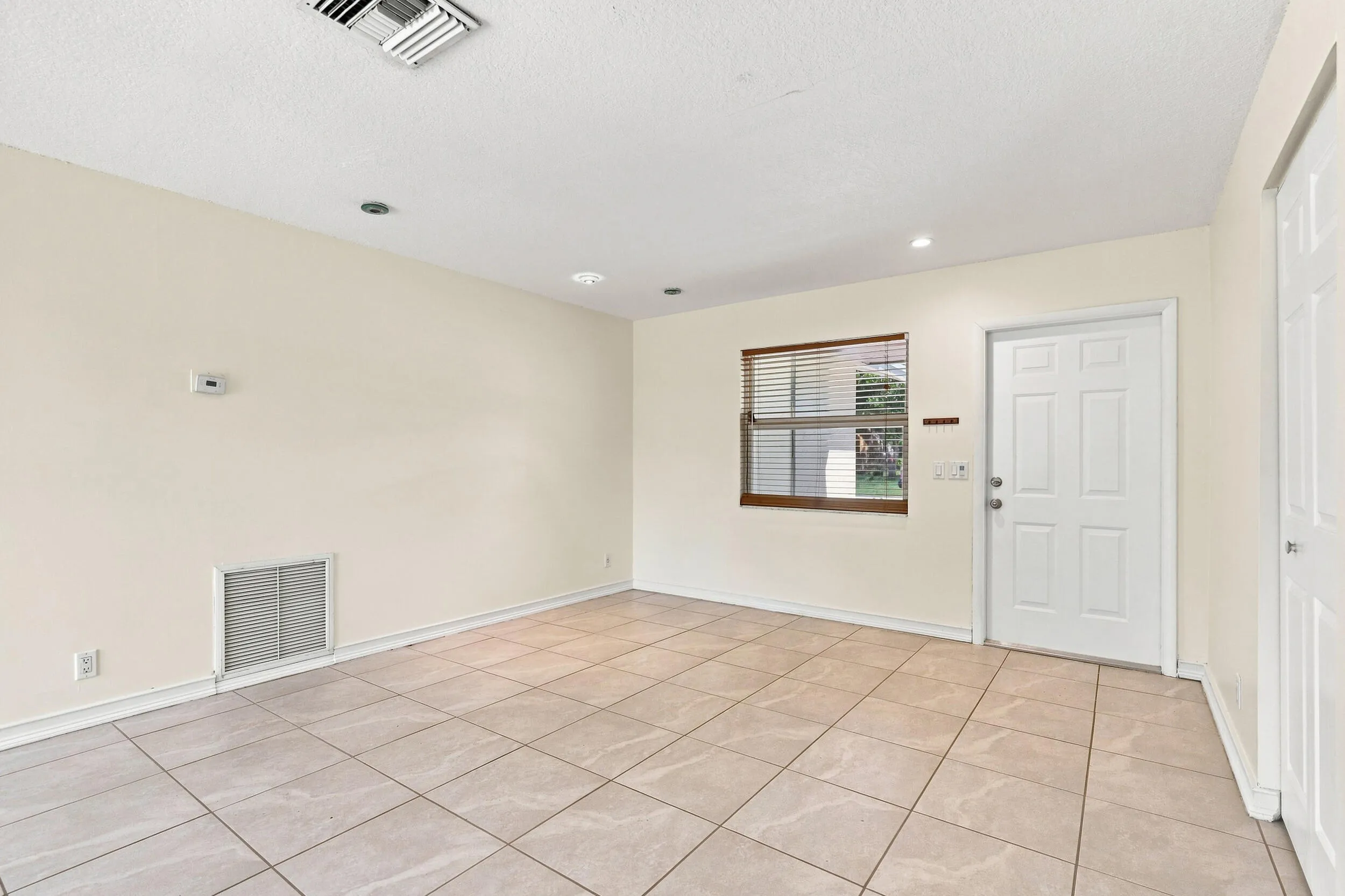 Tiled living space with neutral finishes, recessed lighting, and natural light.