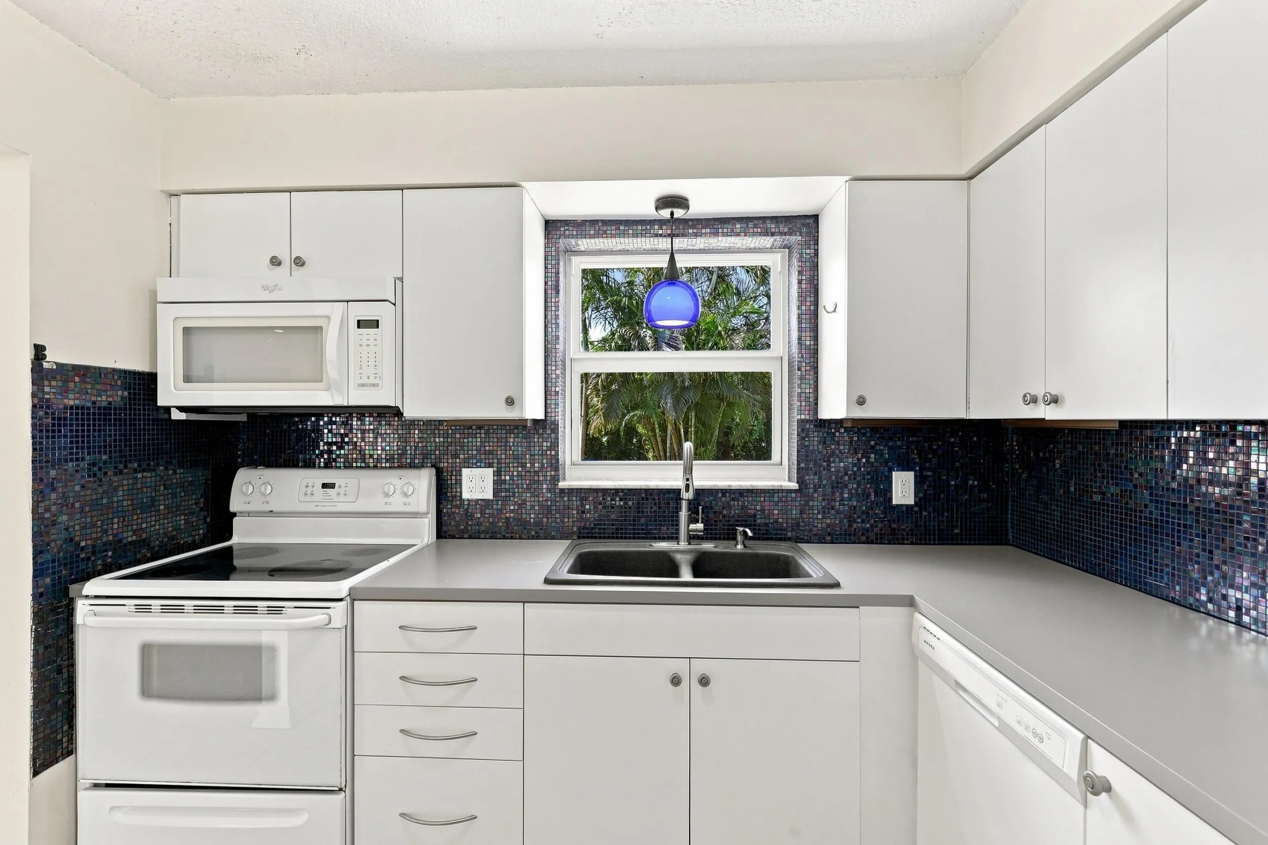 Kitchen featuring white cabinetry, ample counter space, and a window above the sink.