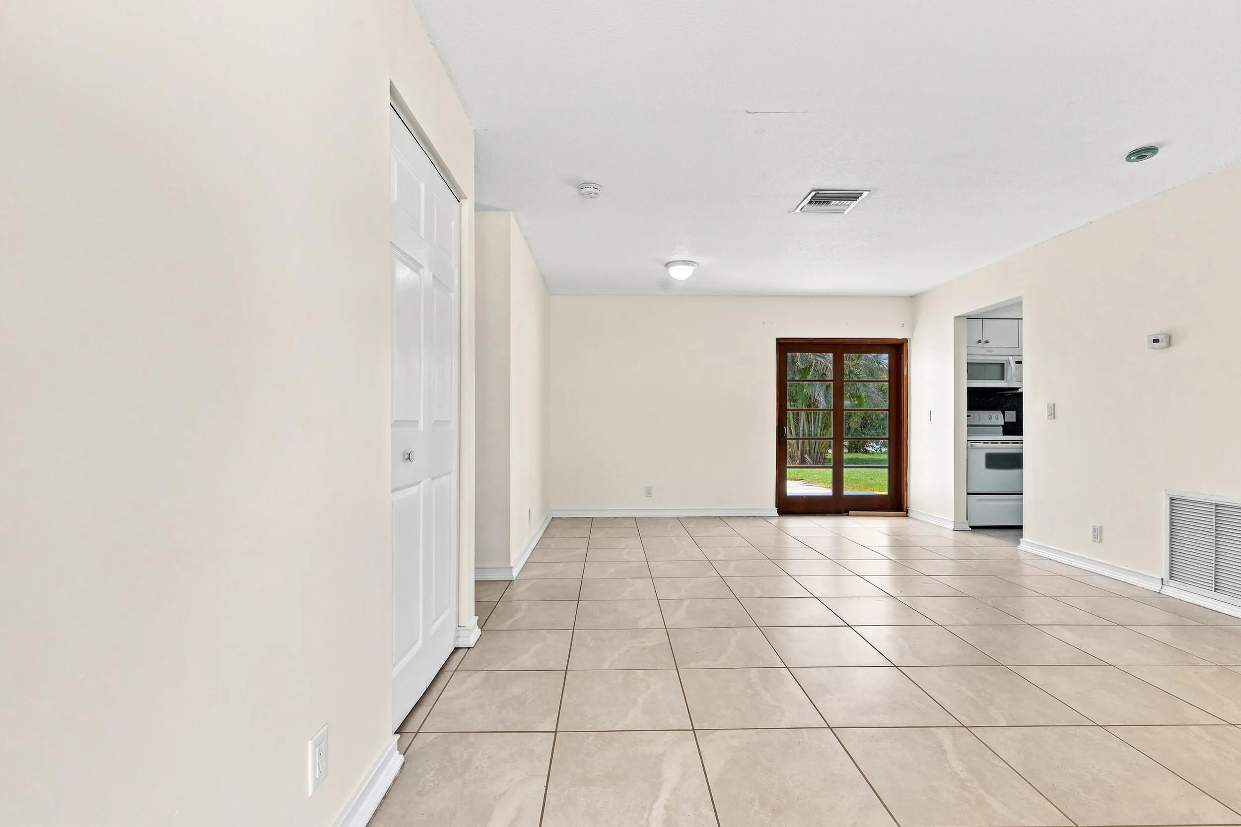 Bright tiled living area with recessed lighting and views toward the rear of the home.