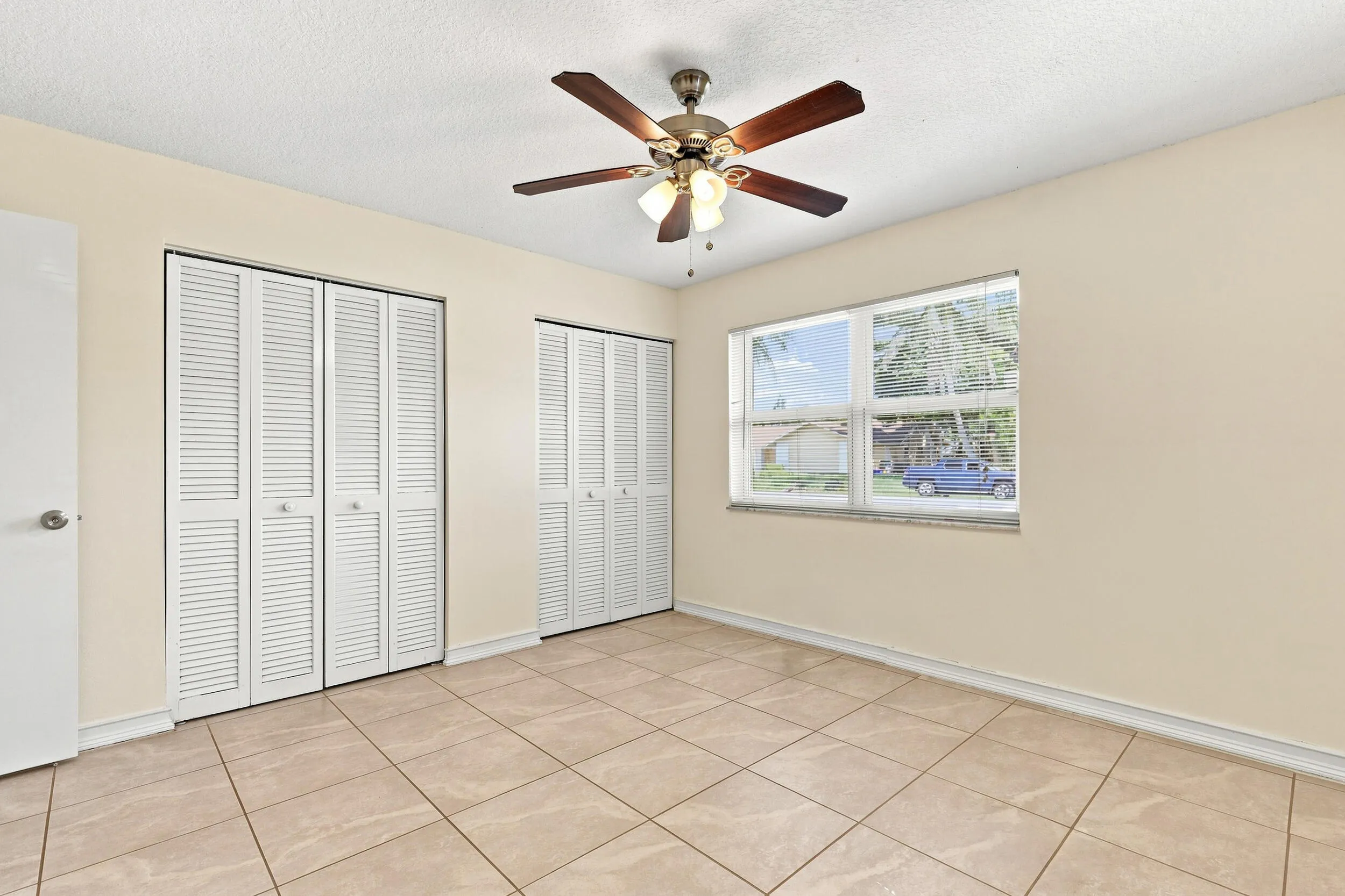 Spacious bedroom featuring tile flooring, ceiling fan, and generous closet space.