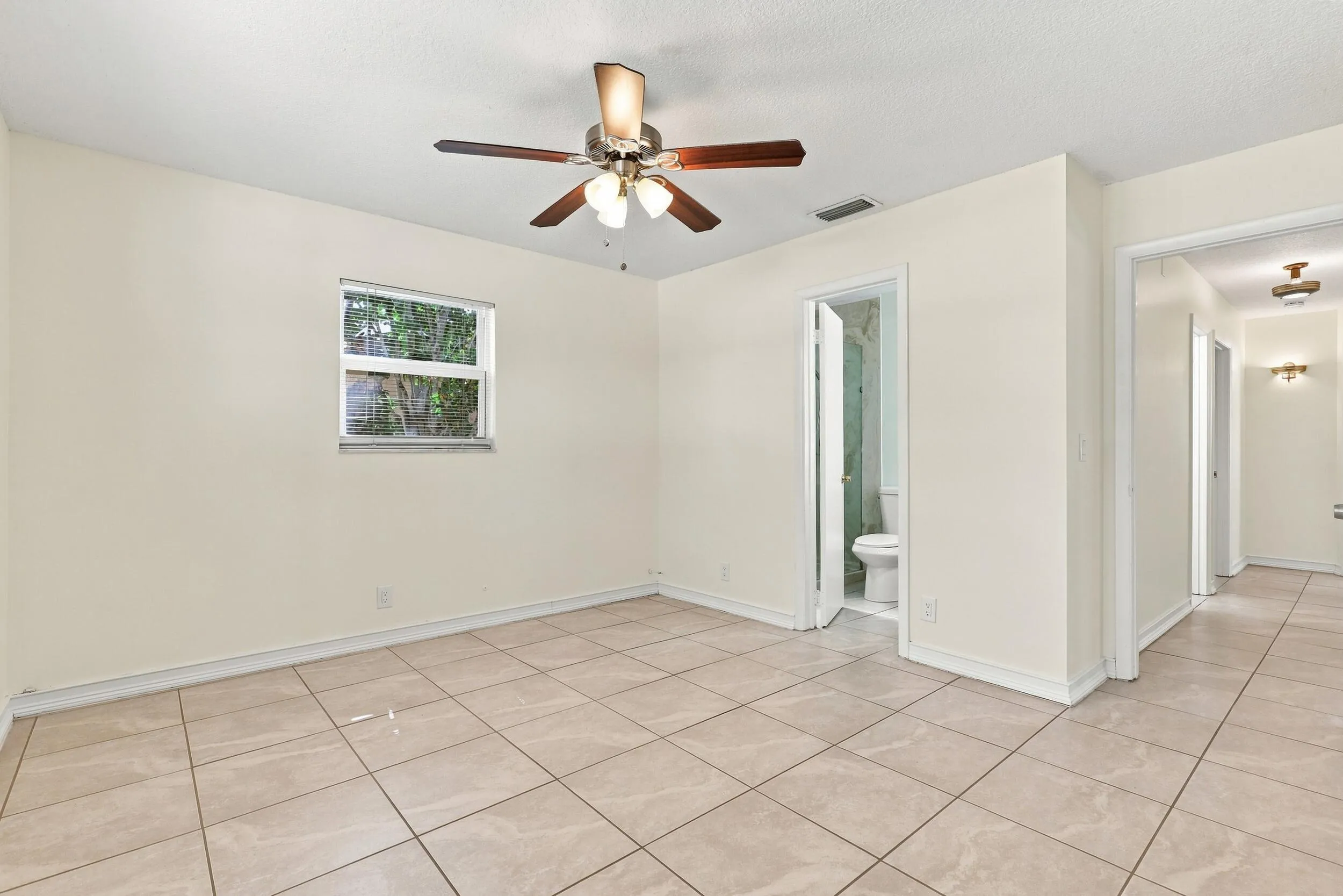 Bright bedroom with tile flooring, ceiling fan, and natural light.