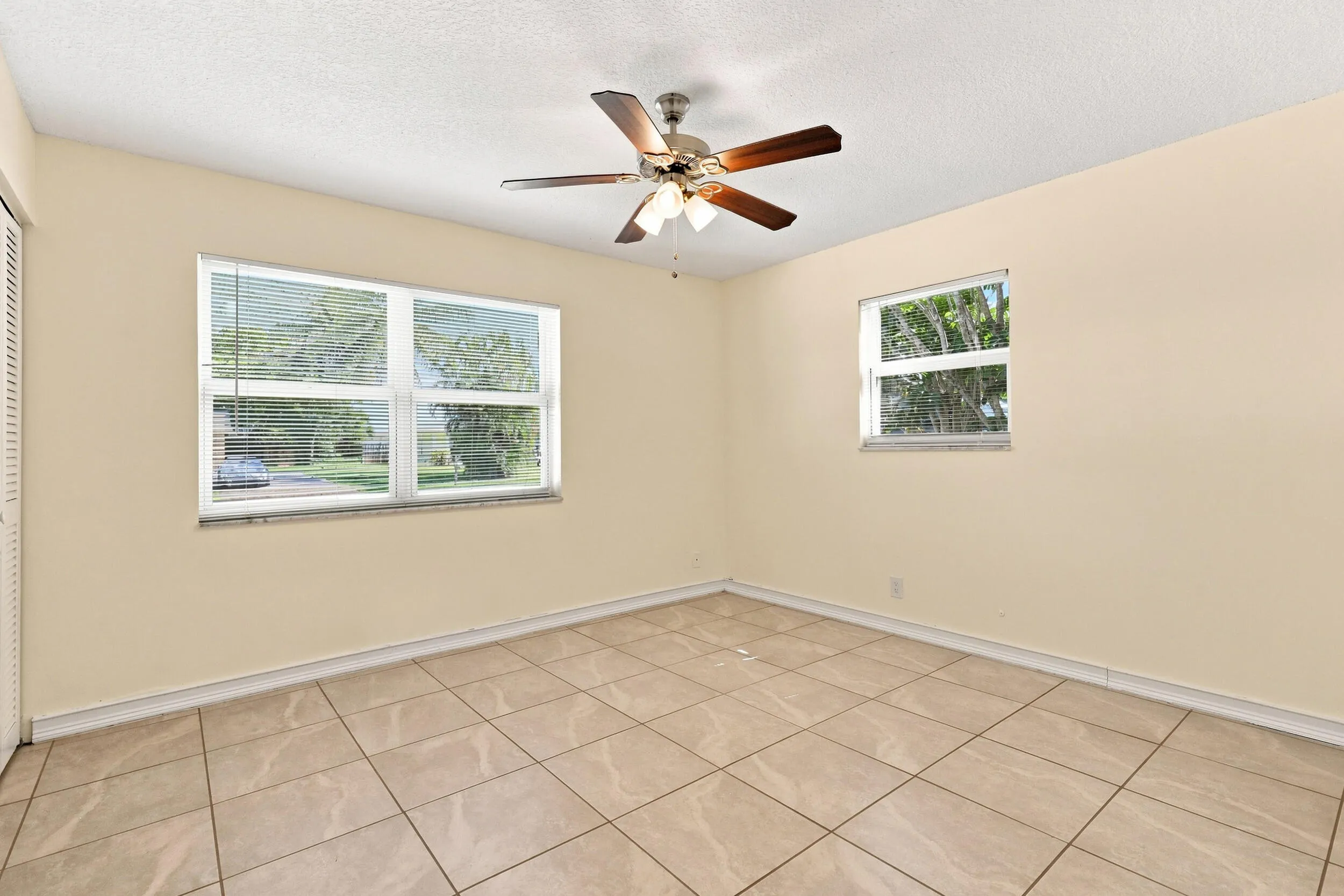 Tiled bedroom with ceiling fan, neutral finishes, and convenient access to the adjoining area.