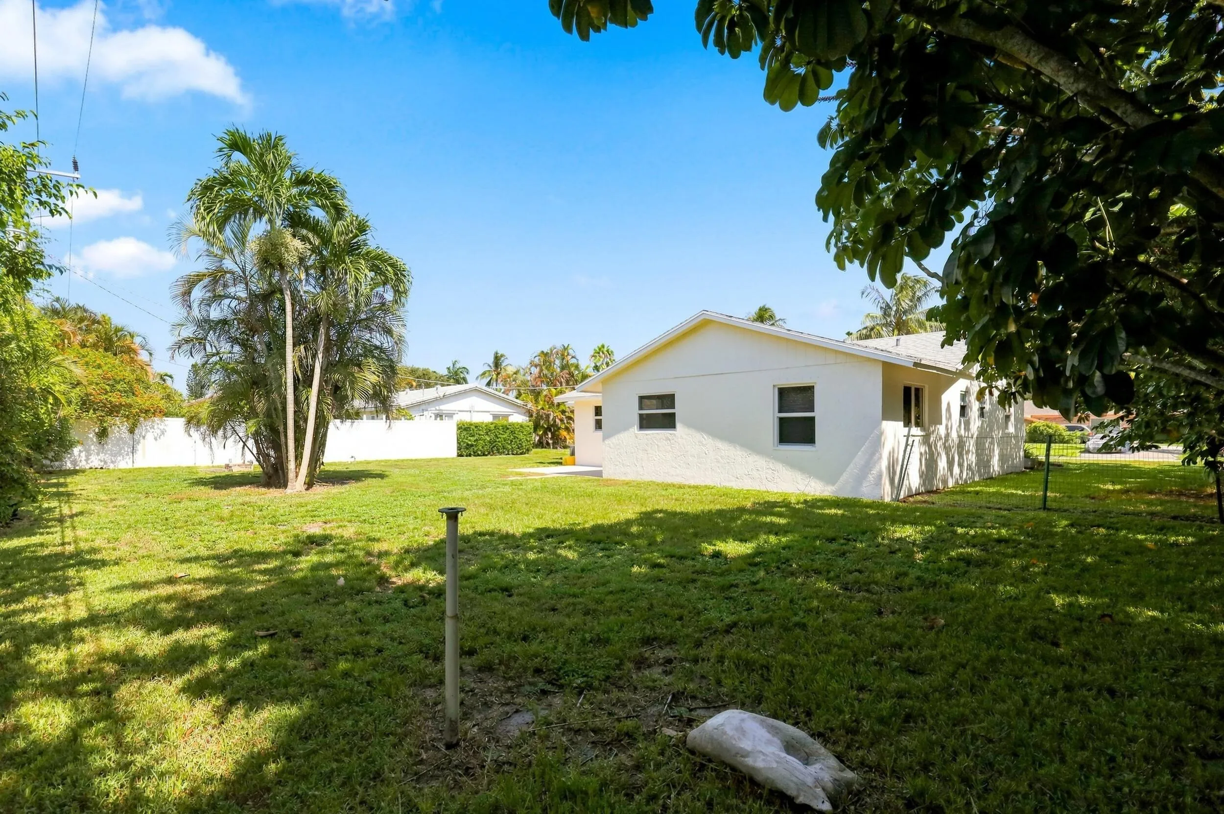 View of the rear of the home featuring a spacious yard and mature trees.