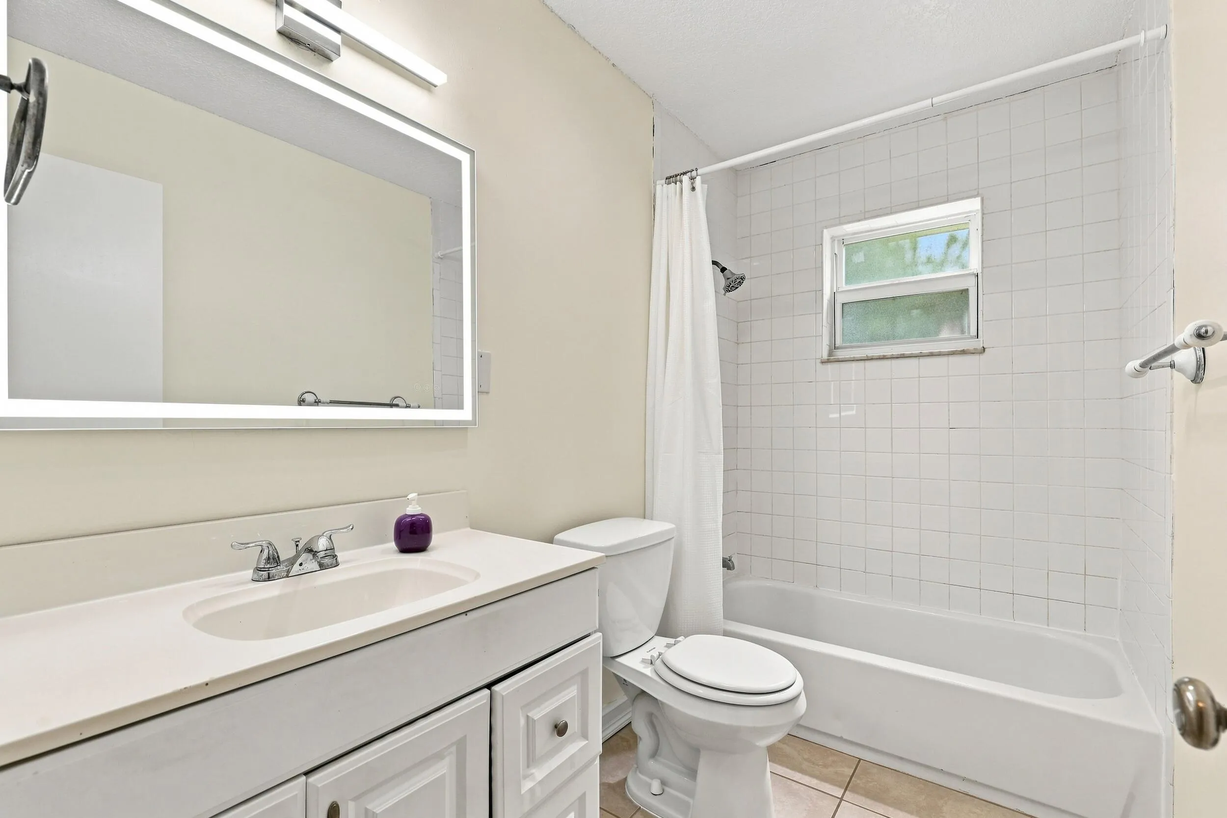 Additional bathroom view highlighting the vanity, tub and shower, and natural light.