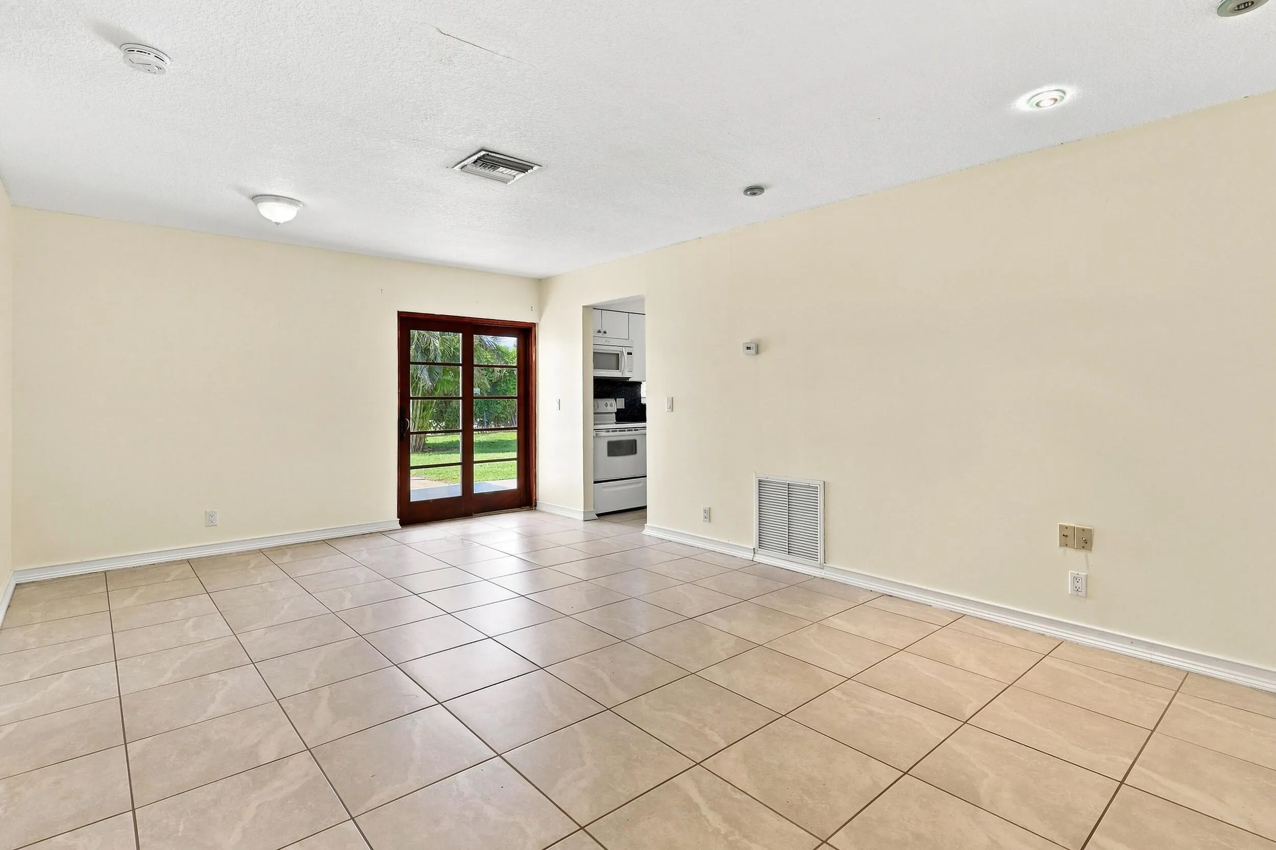 Spacious tiled living area with neutral finishes, recessed lighting, and access to the rear of the home.
