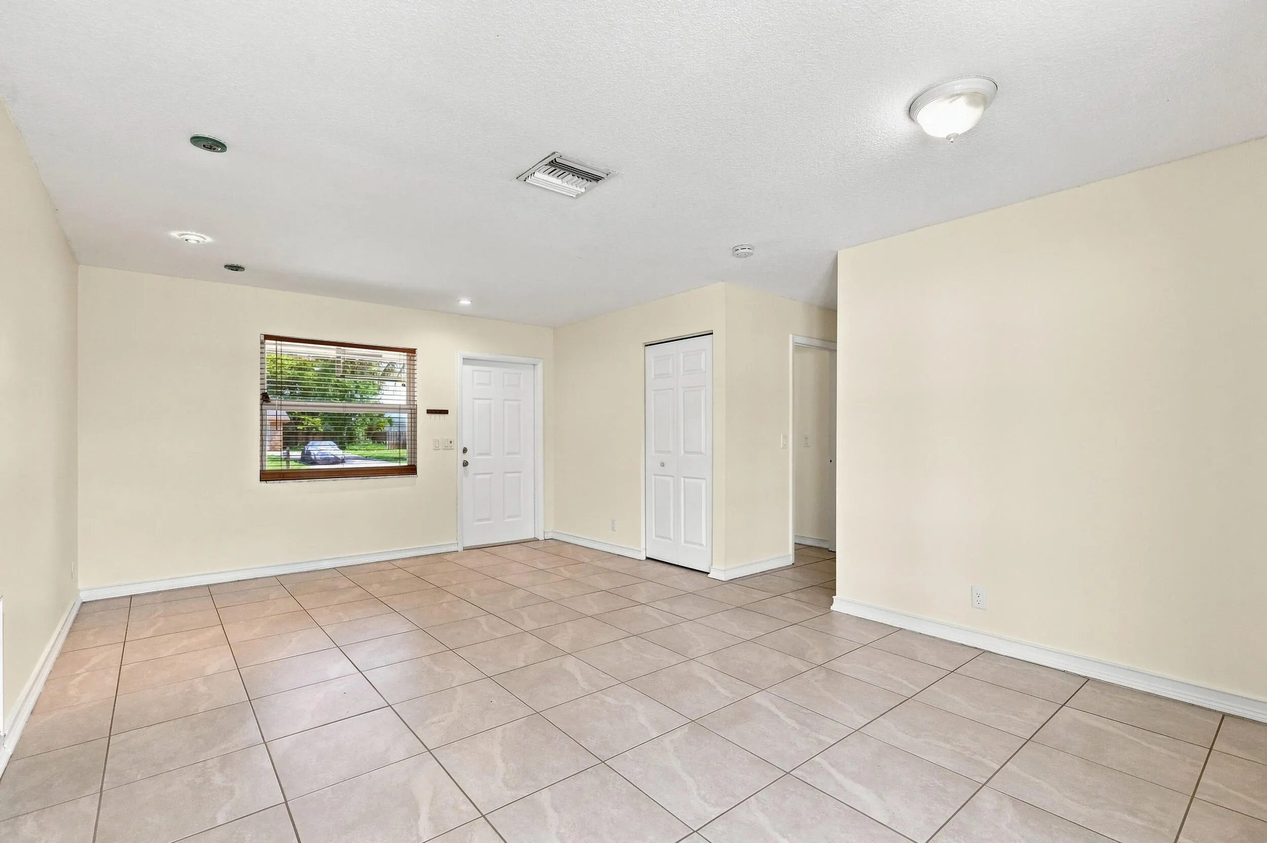 Spacious tiled interior with neutral walls and multiple windows for natural light.
