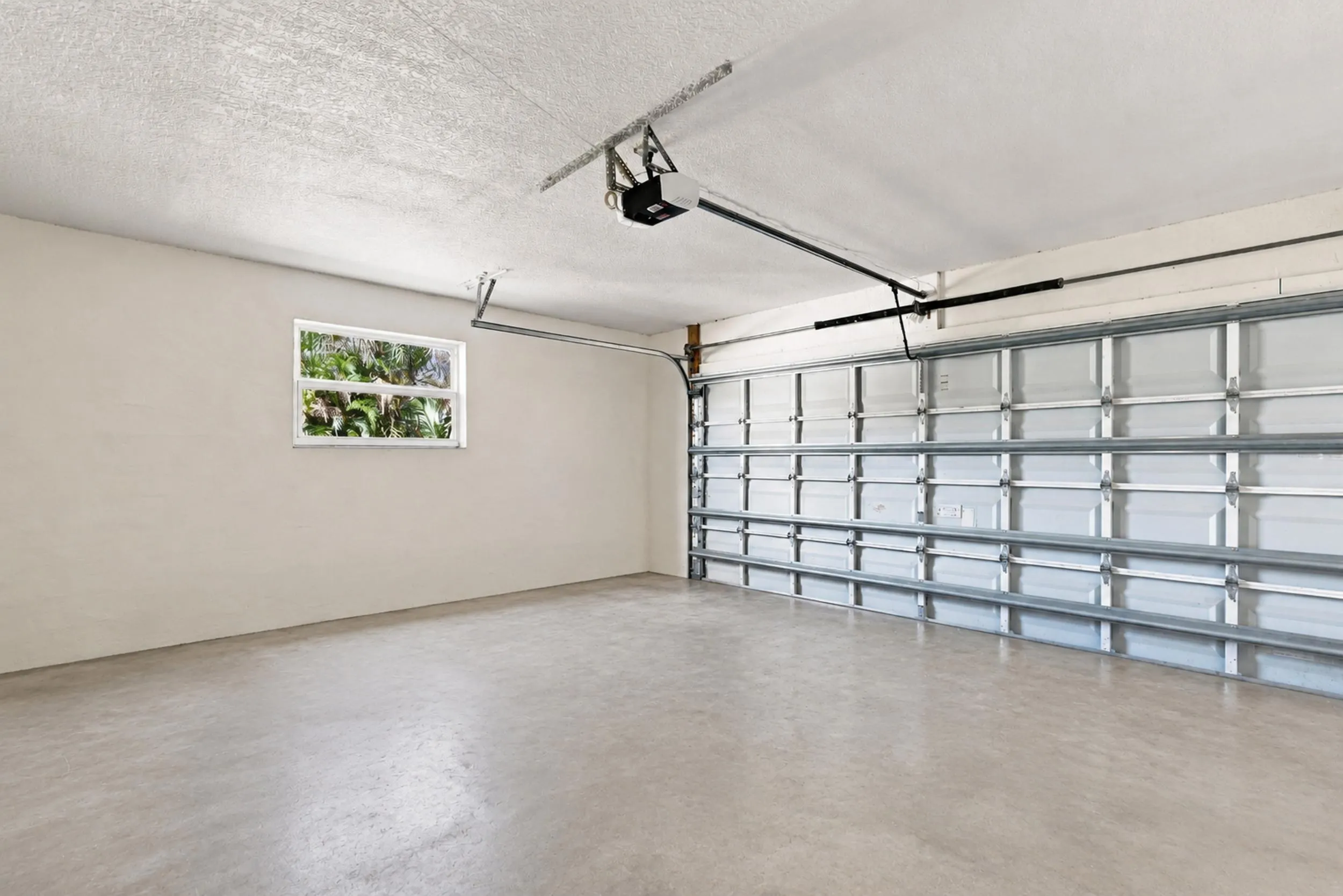 Attached garage with finished walls, overhead garage door, and additional storage space.