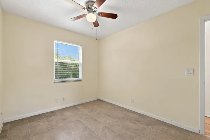 Comfortable bedroom featuring neutral finishes, ceiling fan, and natural light.