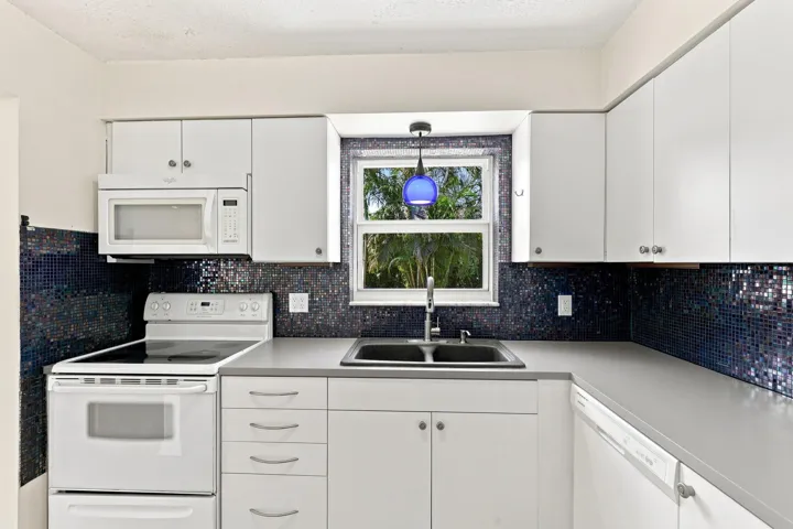 Kitchen featuring white cabinetry, ample counter space, and a window above the sink.