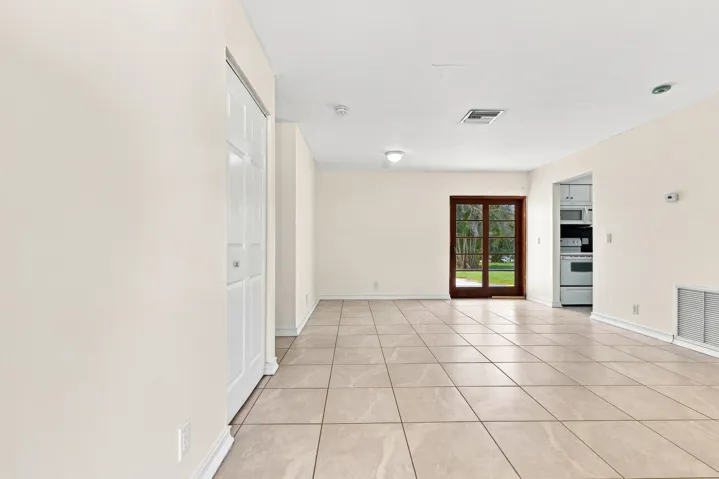 Bright tiled living area with recessed lighting and views toward the rear of the home.