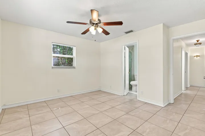 Bright bedroom with tile flooring, ceiling fan, and natural light.