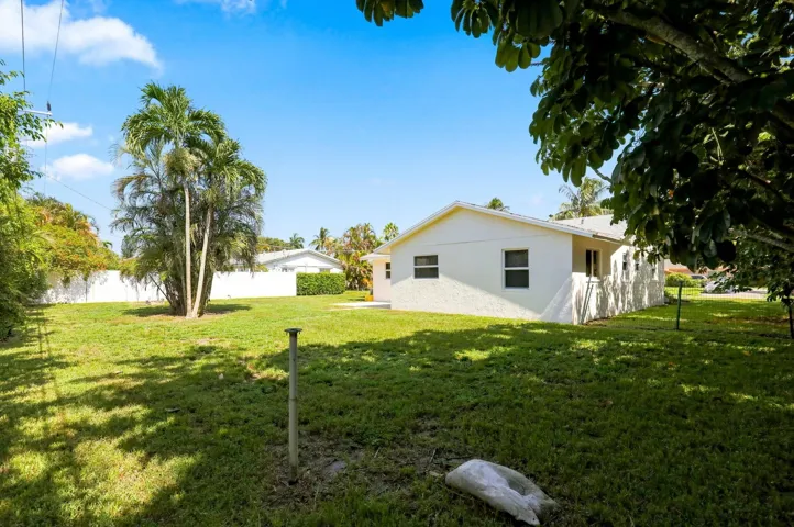 View of the rear of the home featuring a spacious yard and mature trees.